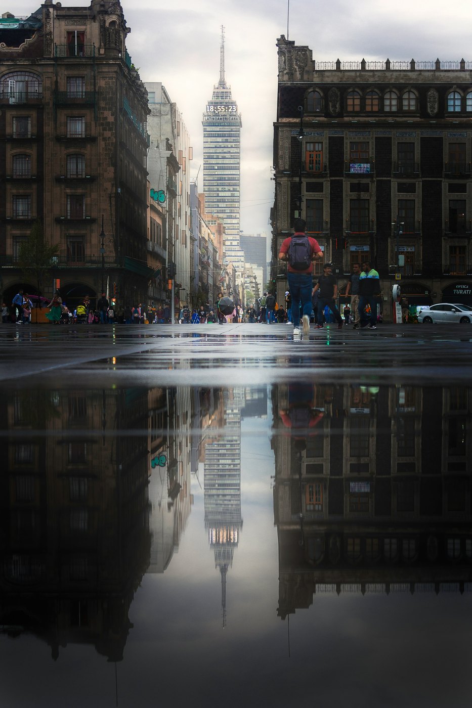 People walking across a rainy Mexico City crosswalk at night.