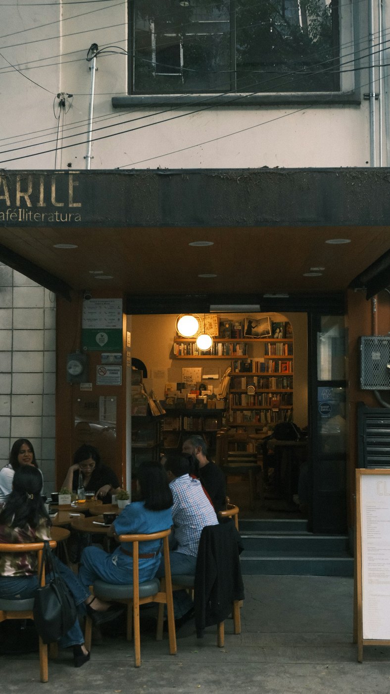 People sitting at tables outside a bookstore cafe in Mexico City.