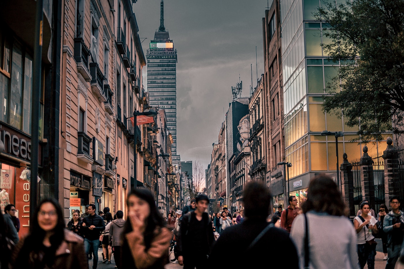 People walking on a busy Mexico City pedestrian street at dusk.