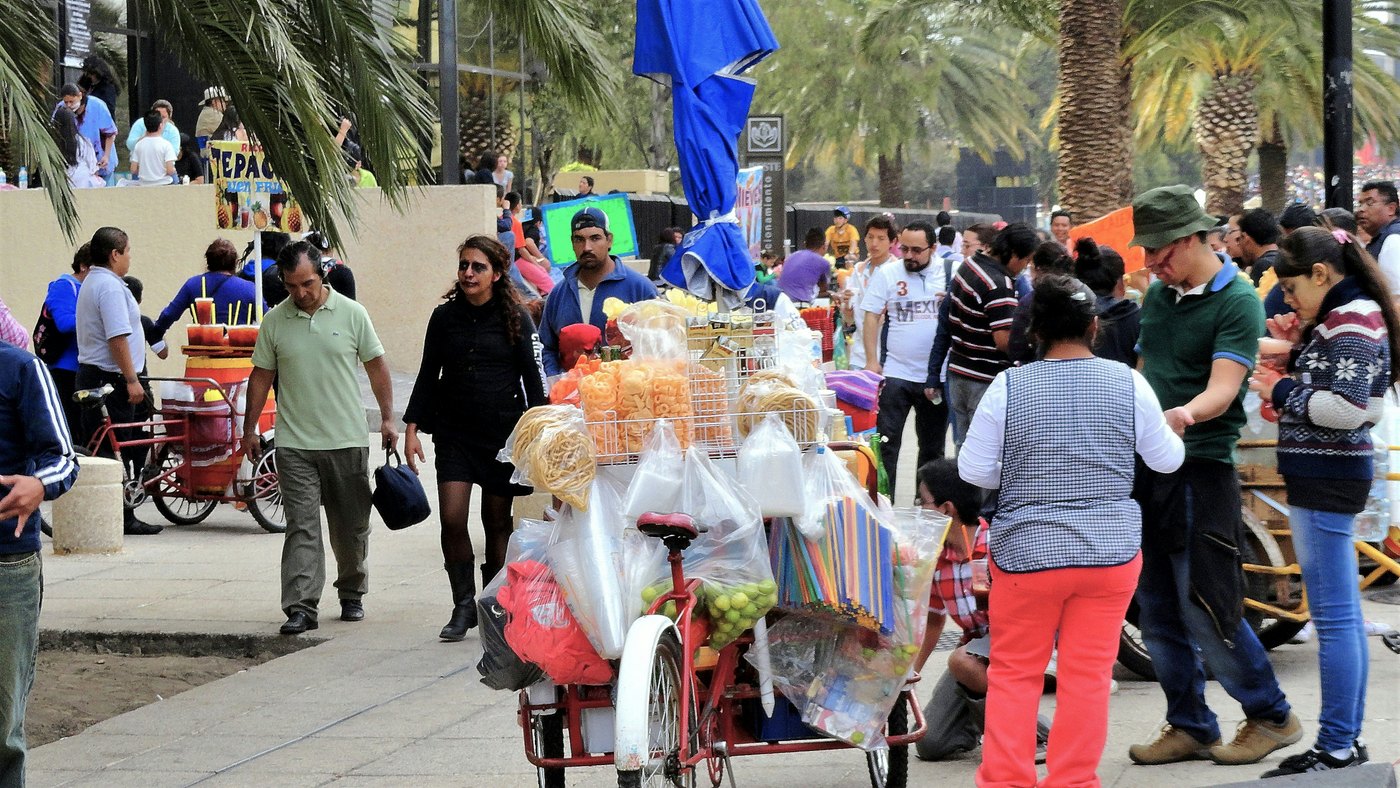 People standing by street vendors and storefronts in Mexico City.