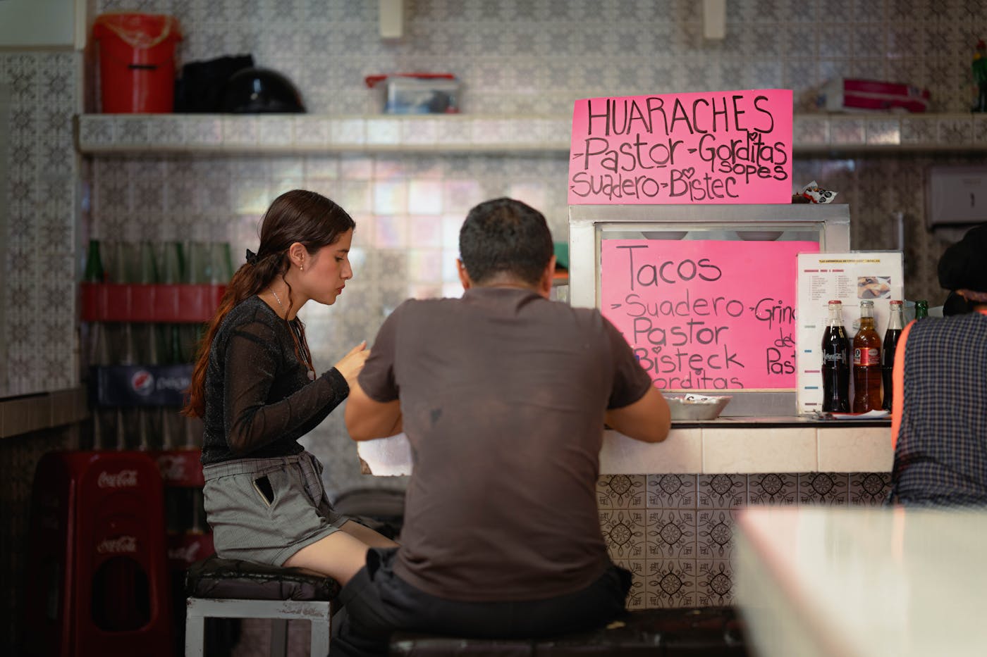 Two people sitting at a street food counter in Ciudad de Mexico.