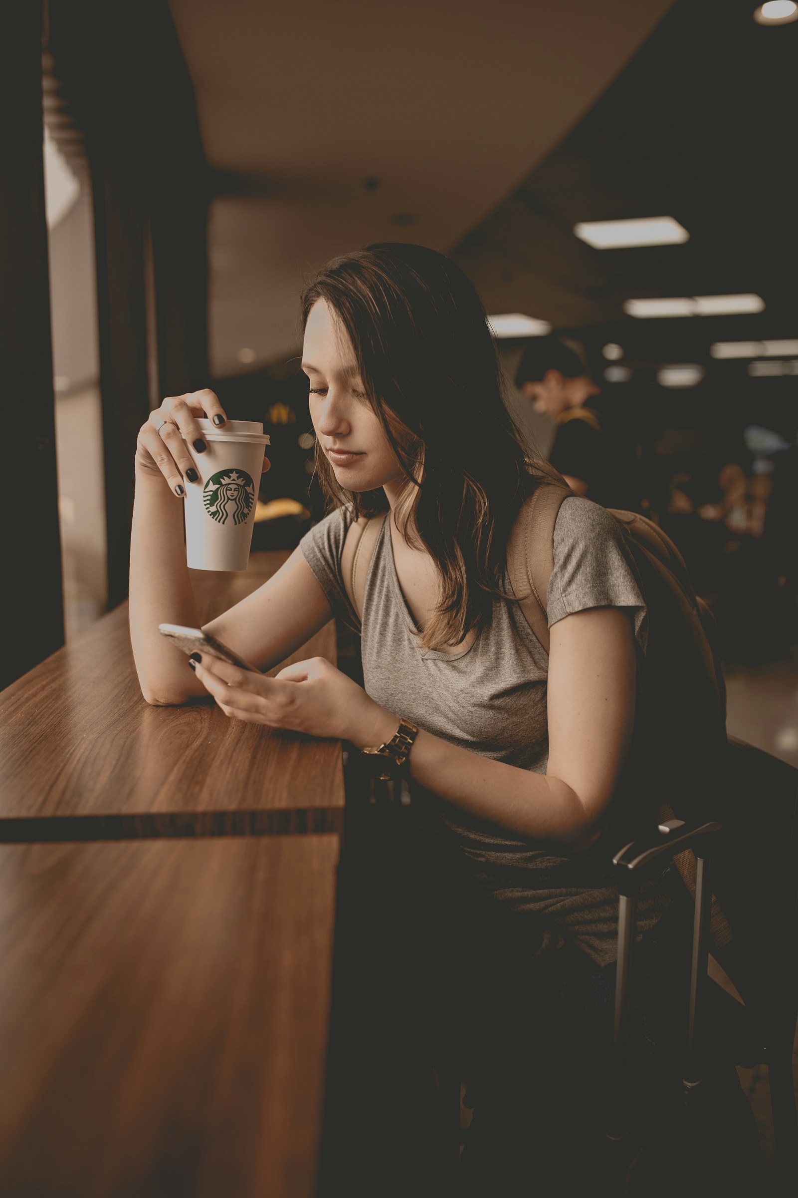 A phone beside a coffee cup on a table.