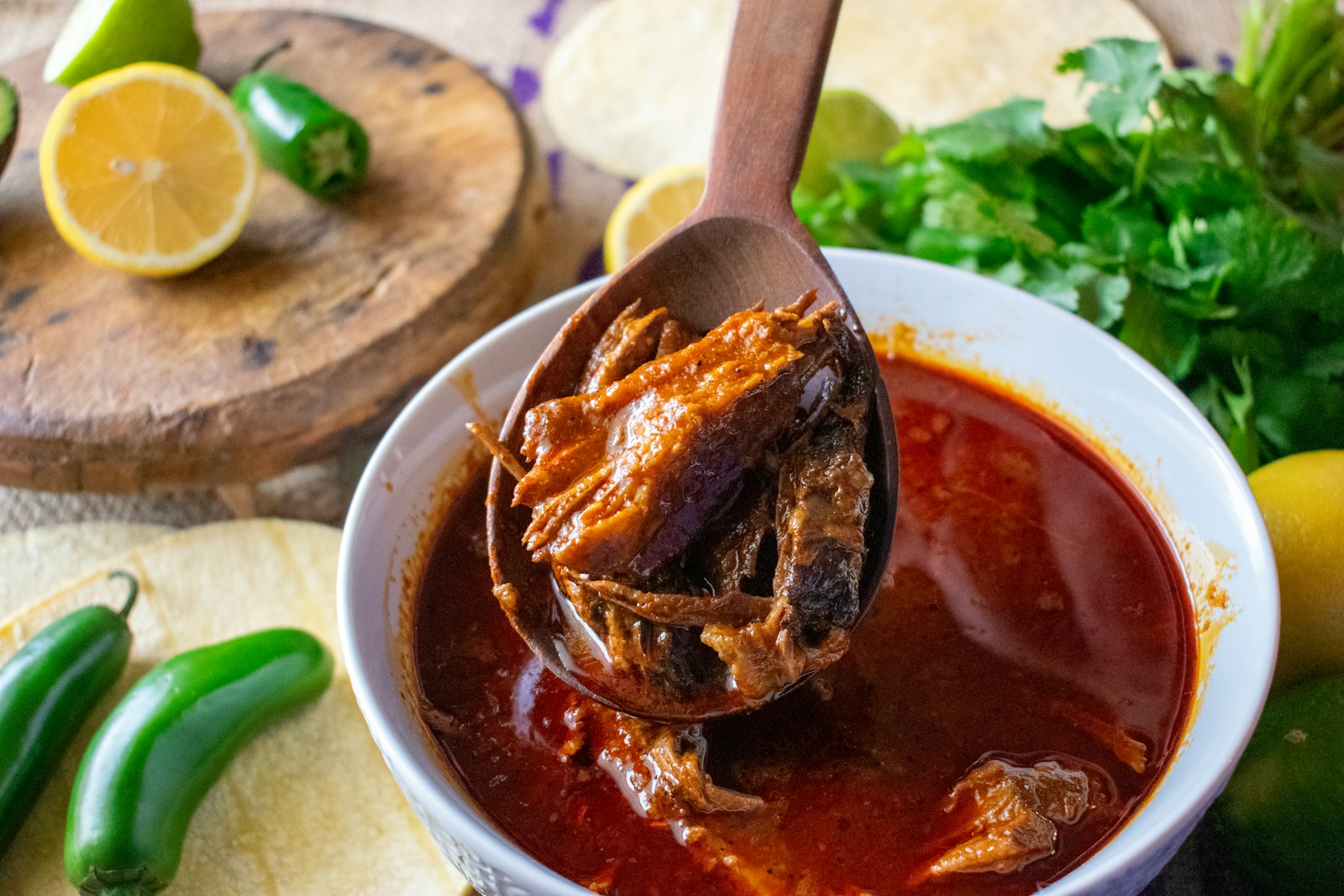 A hearty bowl of Mexican stew served with lime wedges and dried chillies on the side.