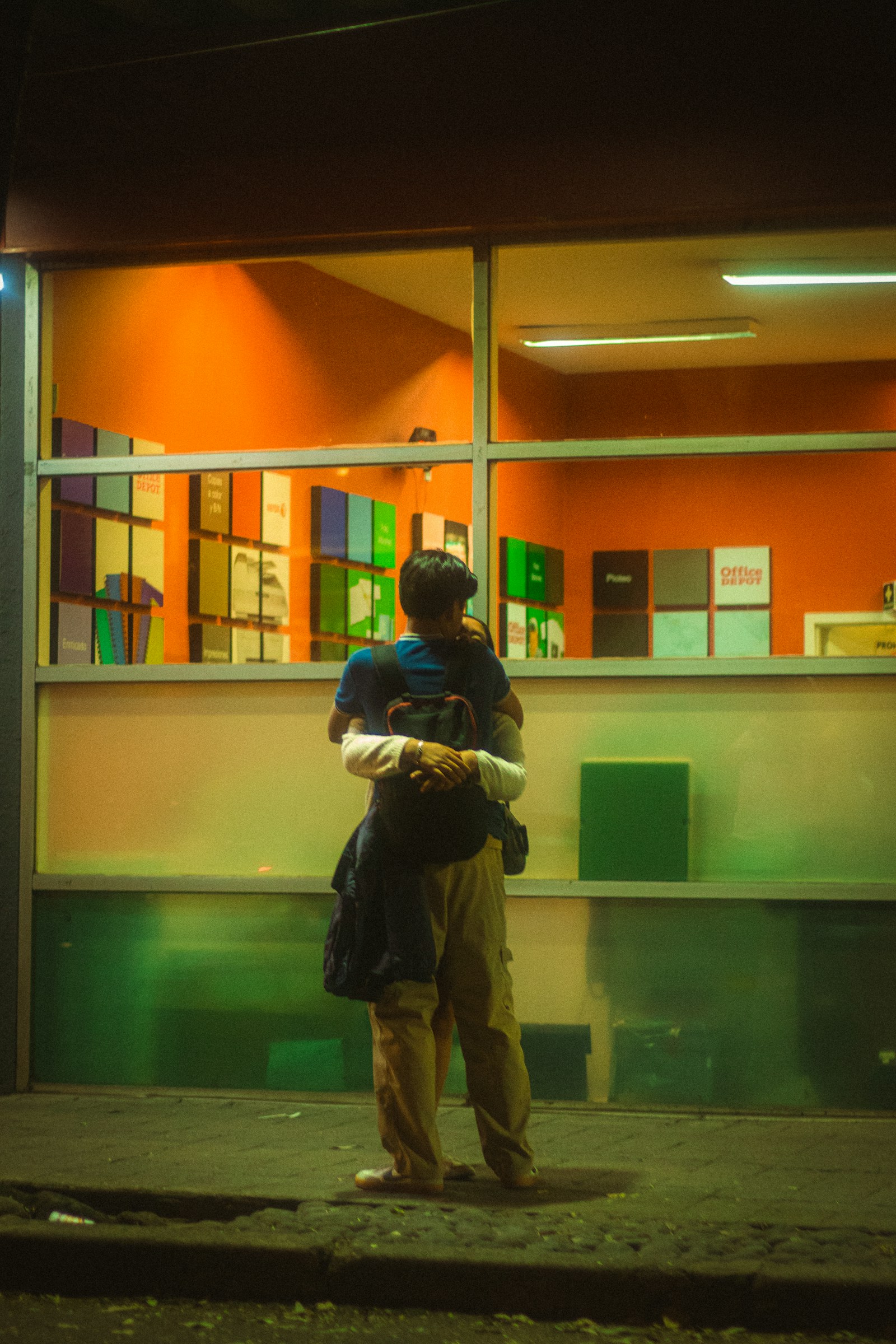 A couple standing close together by a window.