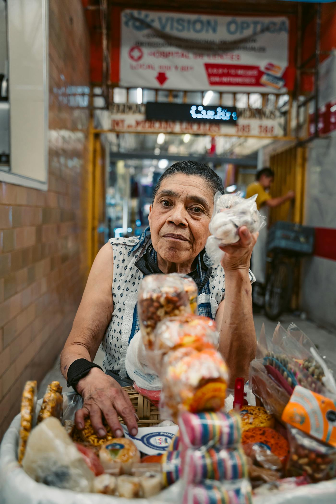 An older street vendor selling snacks in a narrow Mexico City alley.