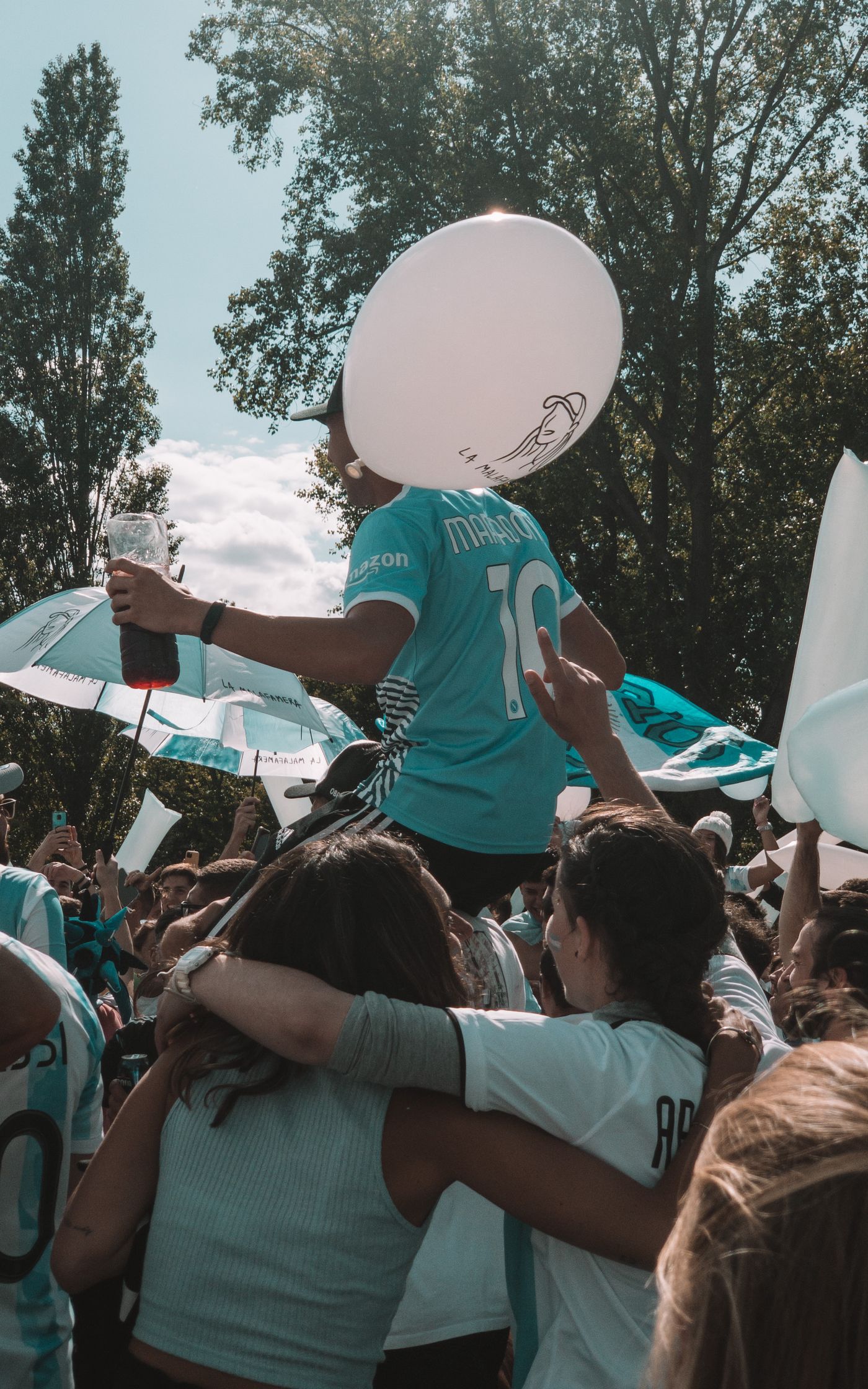 Fans outdoors celebrating together with a large balloon overhead.