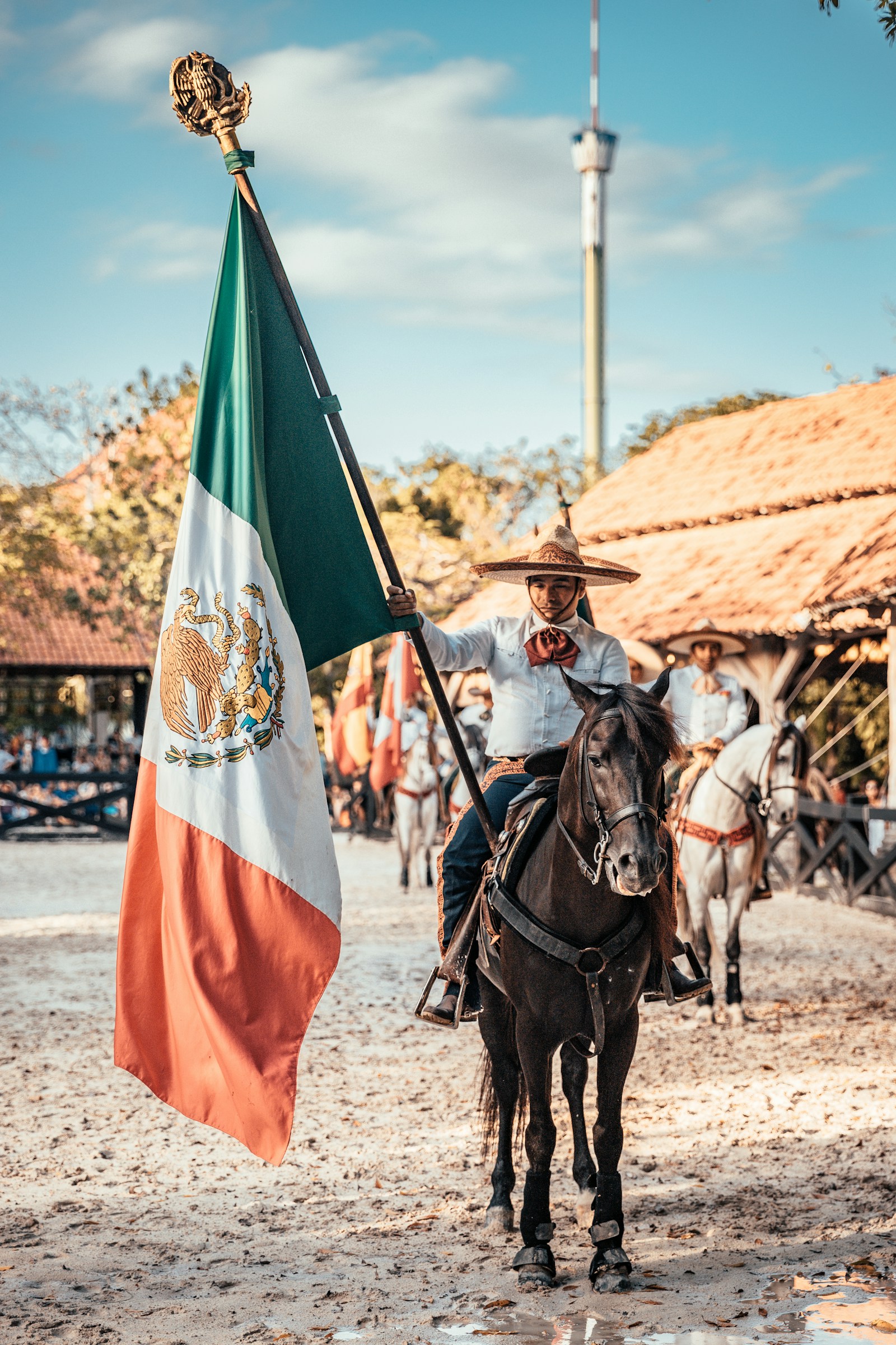 A man on horseback holding a large Mexican flag.