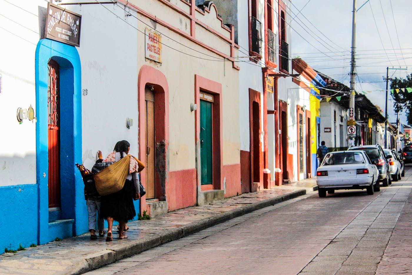 People walking near colorful buildings on a street in Mexico.