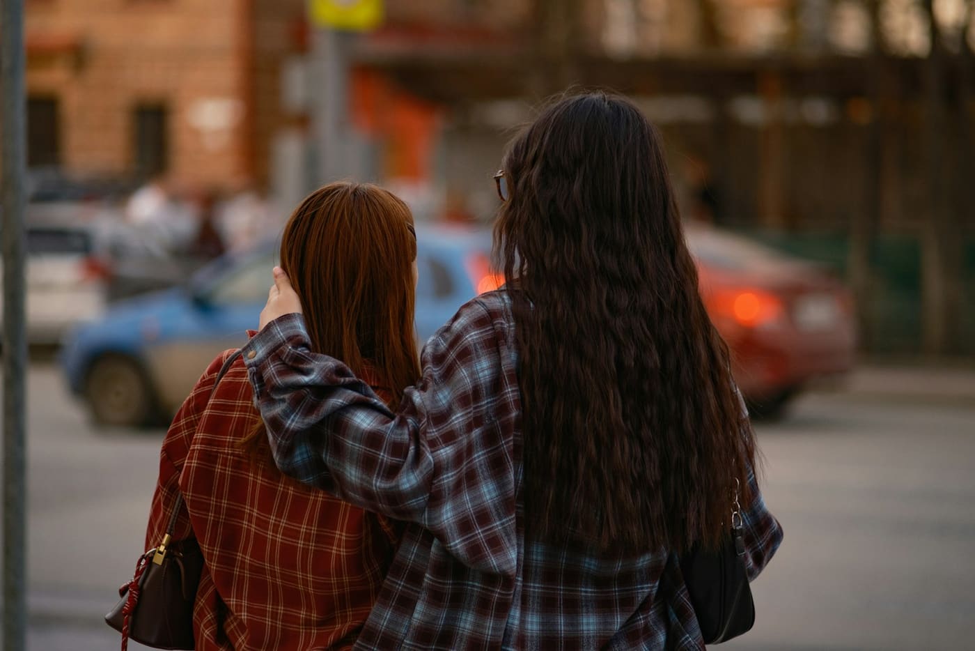 Two women walking arm in arm down a street.