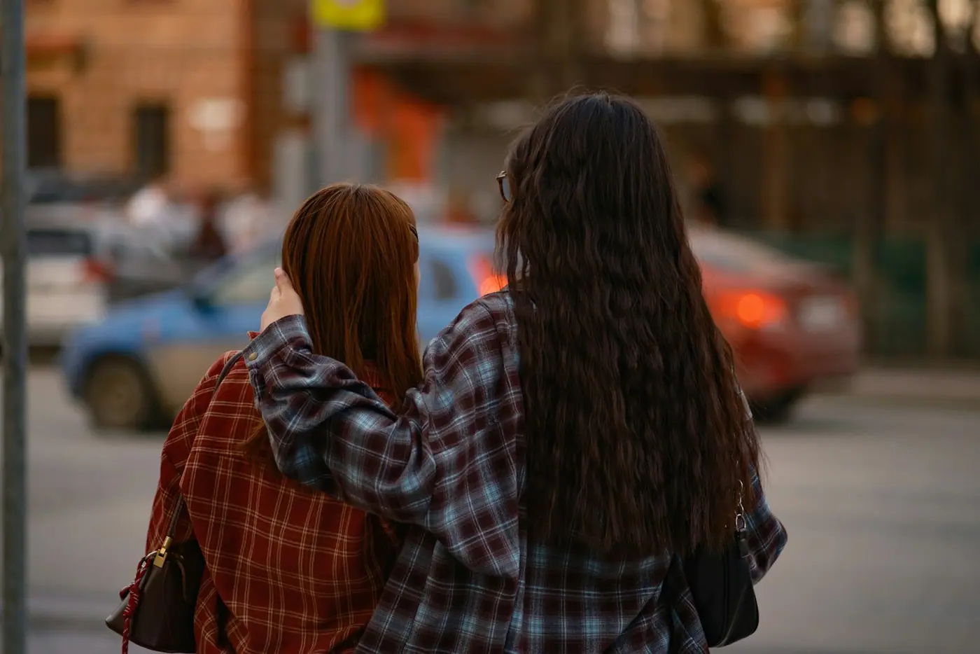 Two women walking arm in arm down a street.
