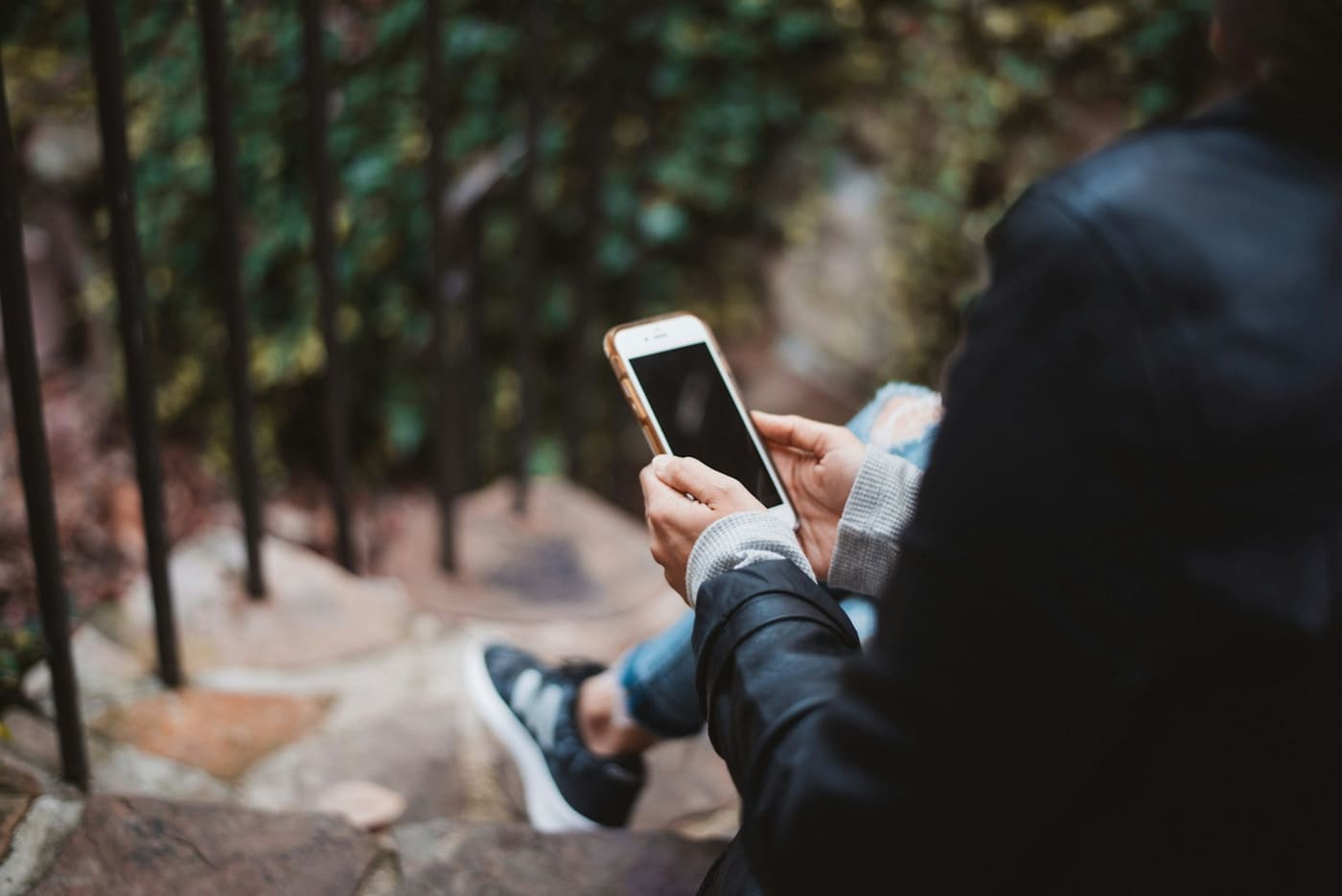 A person sitting on a step, typing on a phone.