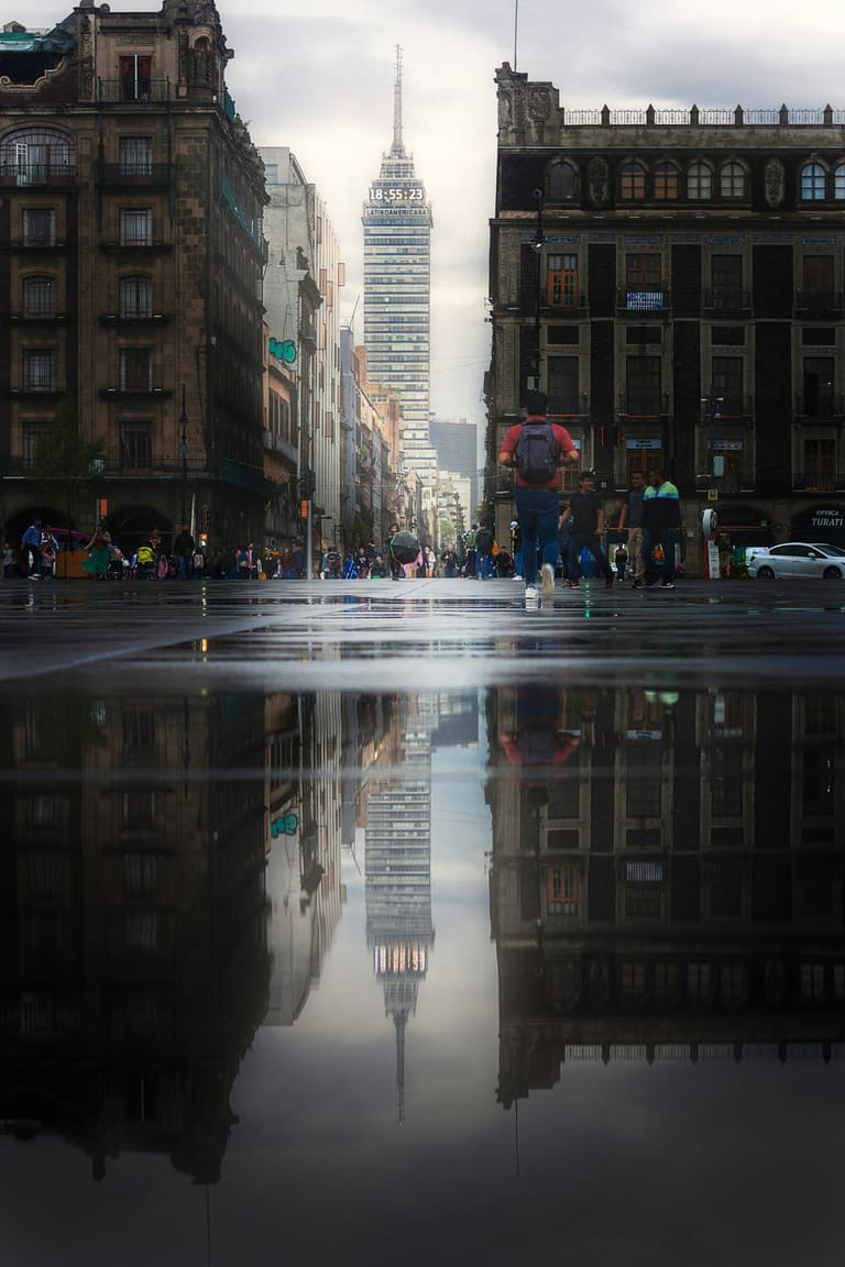 People walking across a rainy Mexico City crosswalk at night.