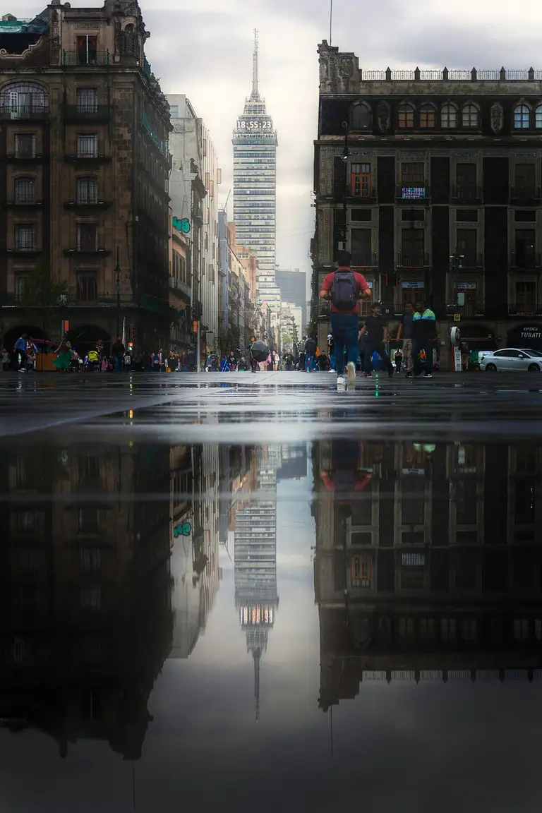 People walking across a rainy Mexico City crosswalk at night.