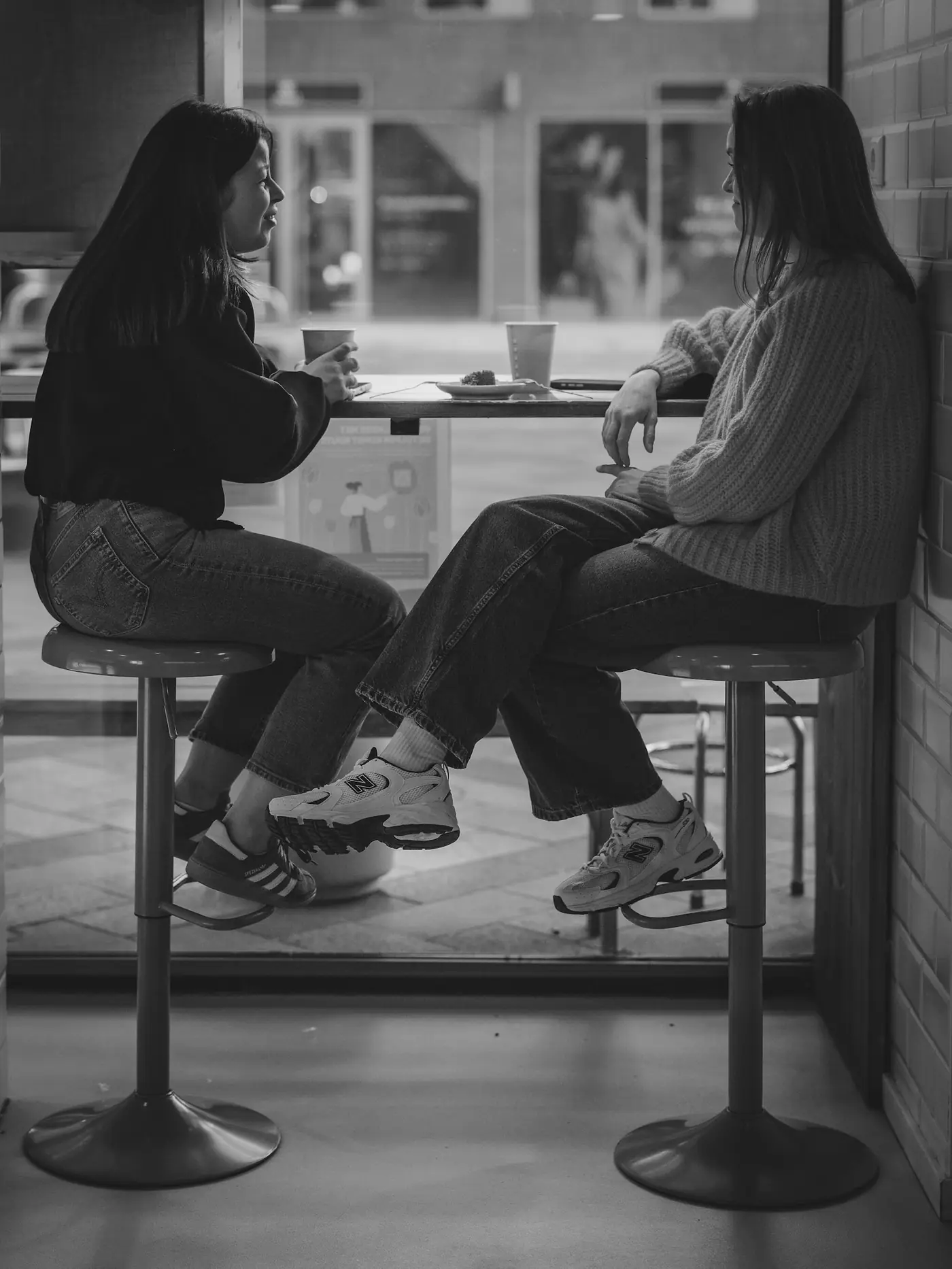 Two people sitting on stools at a counter in a black and white photograph.