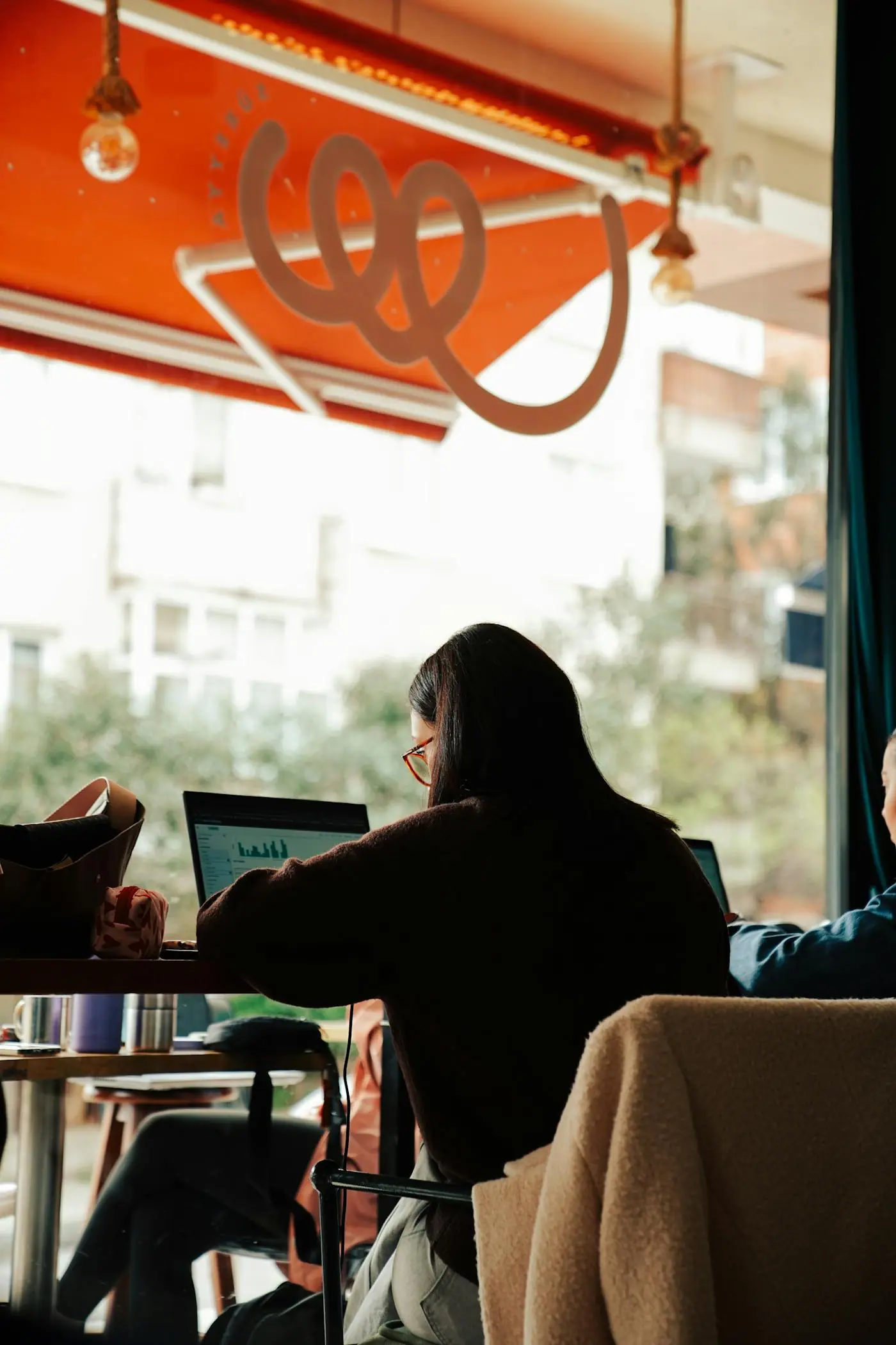 People working on laptops at a cafe table.