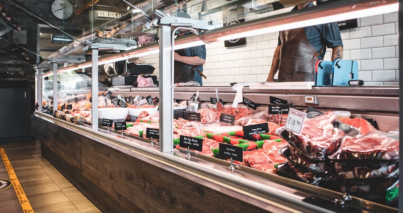 Butcher shop display counter with fresh cuts of meat laid out behind glass.