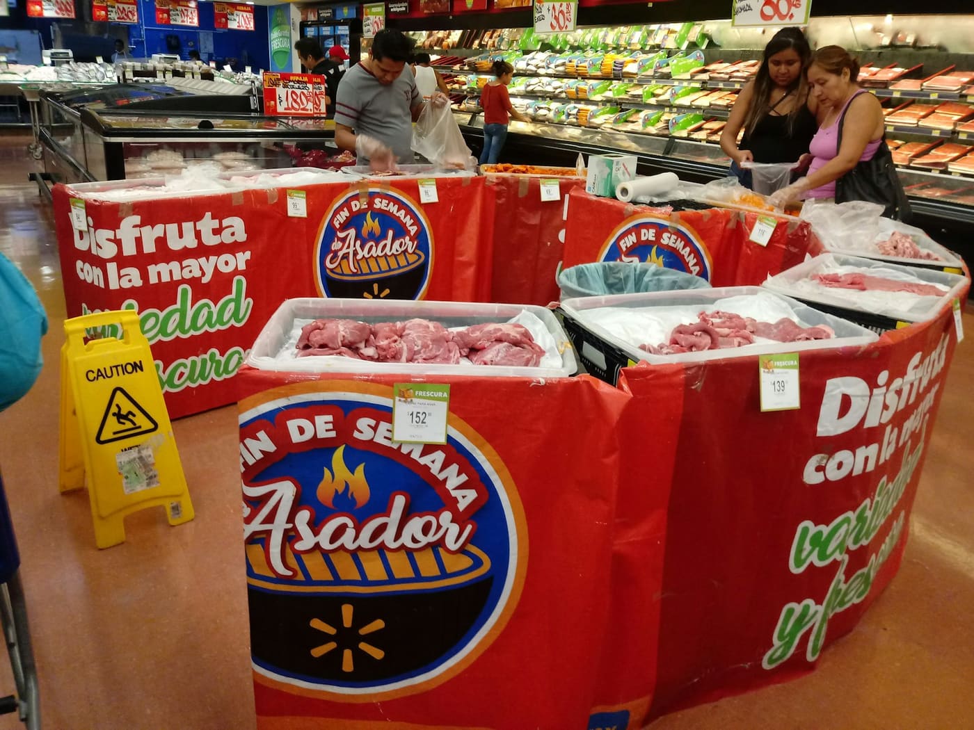 Supermarket meat counter with packaged cuts and Spanish-language signage above the display.