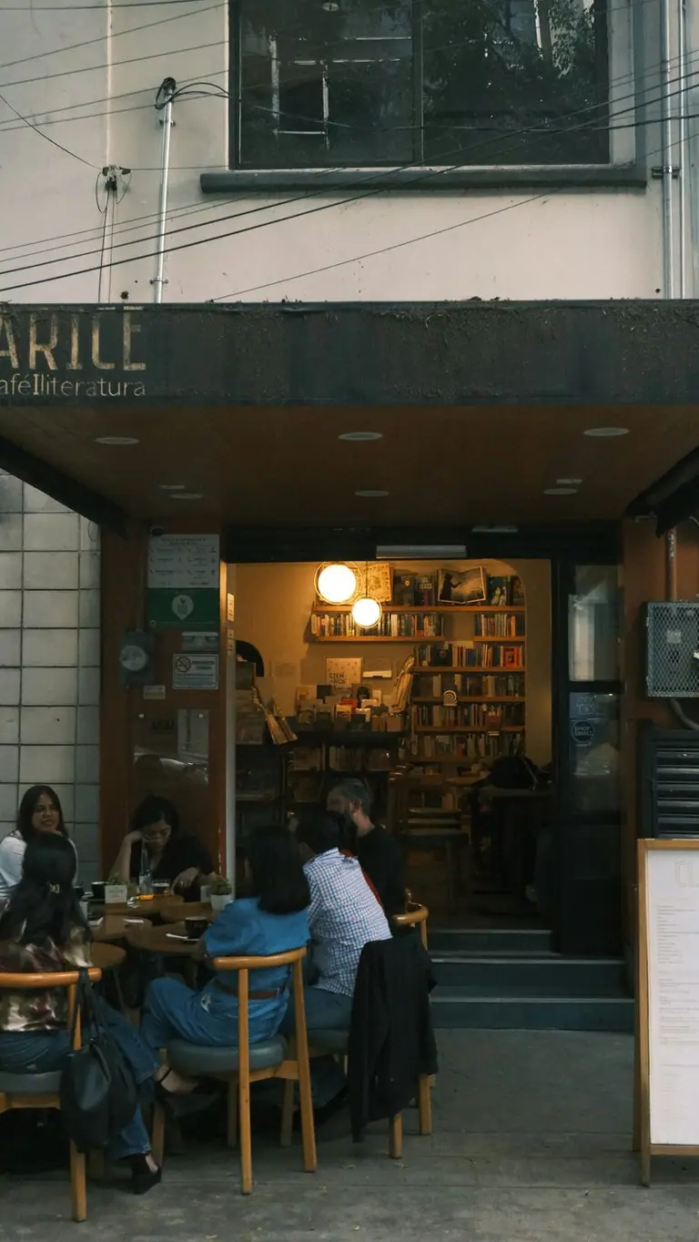 People sitting at tables outside a bookstore cafe in Mexico City.