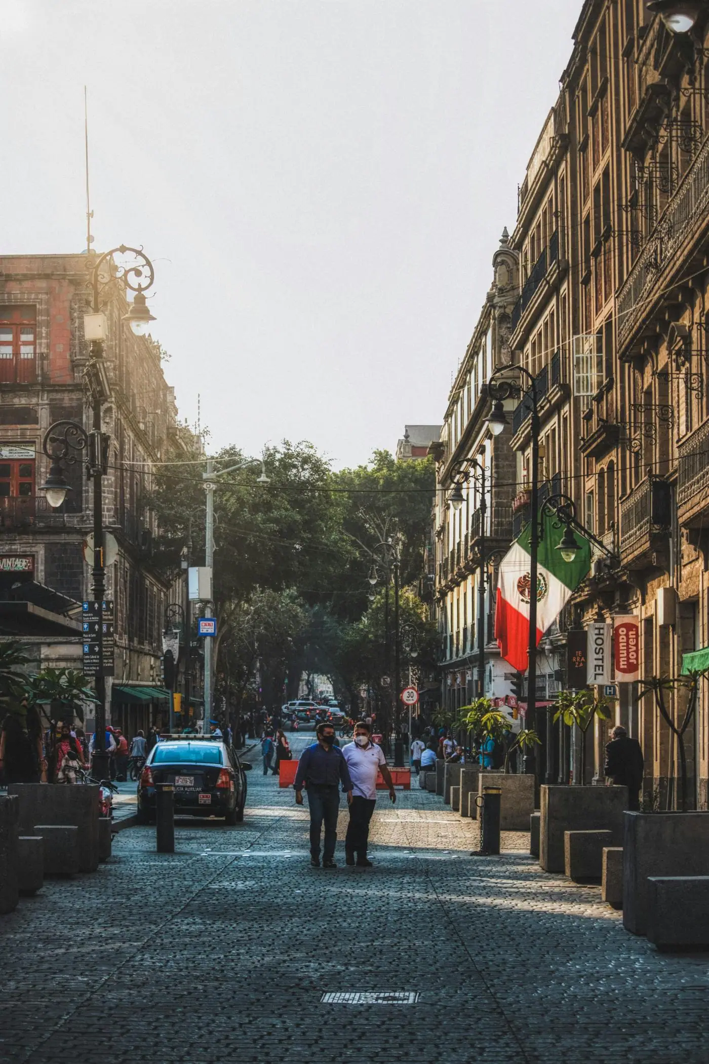 People walking through an older street in Mexico City.