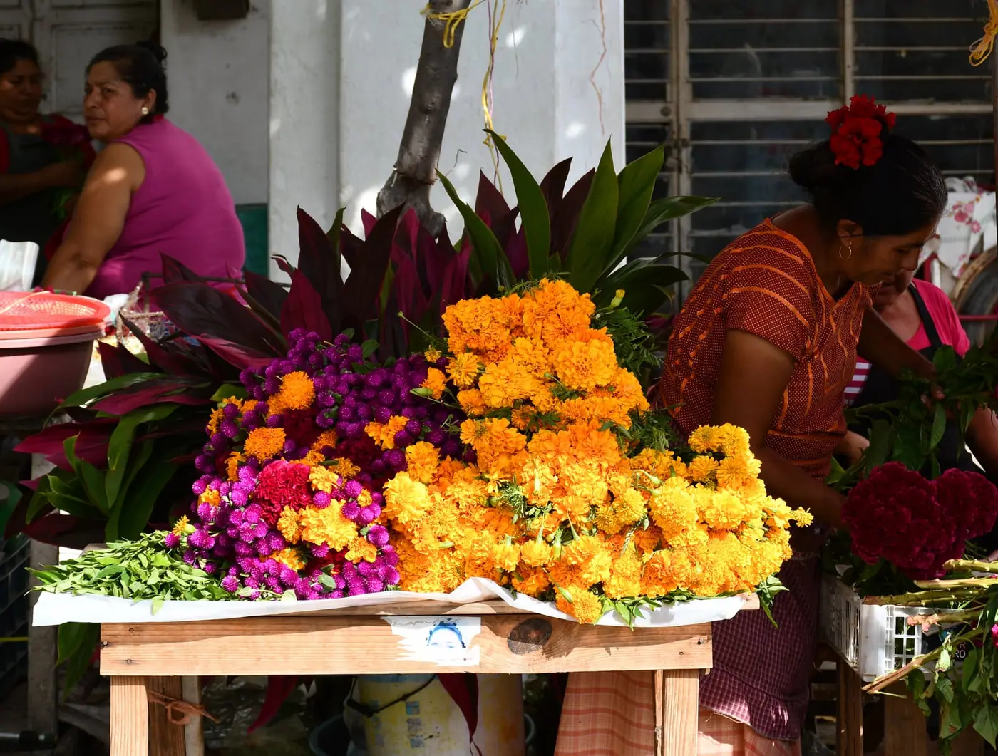 A market flower stall stacked with orange and magenta Day of the Dead flowers
