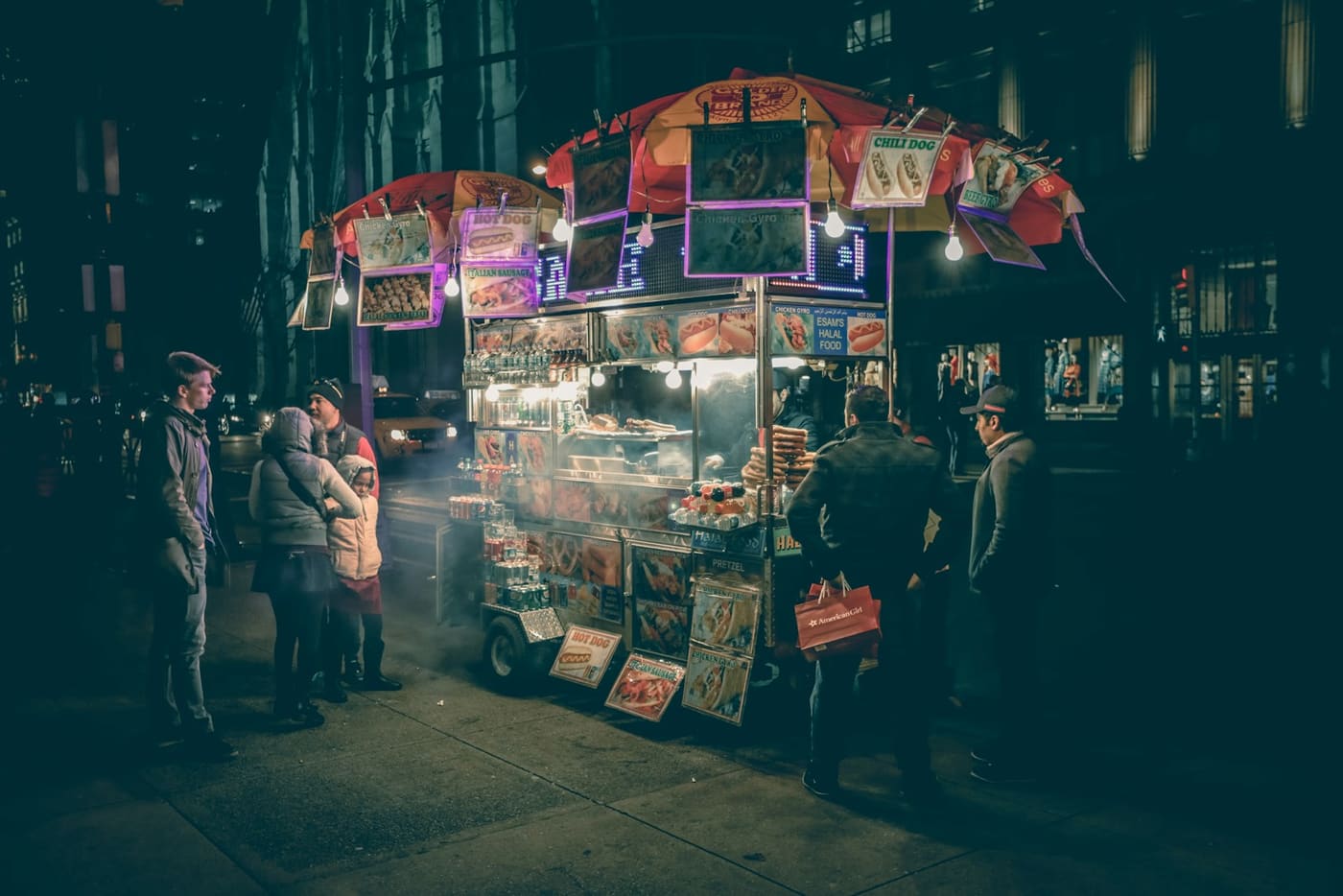People standing around a street food cart.