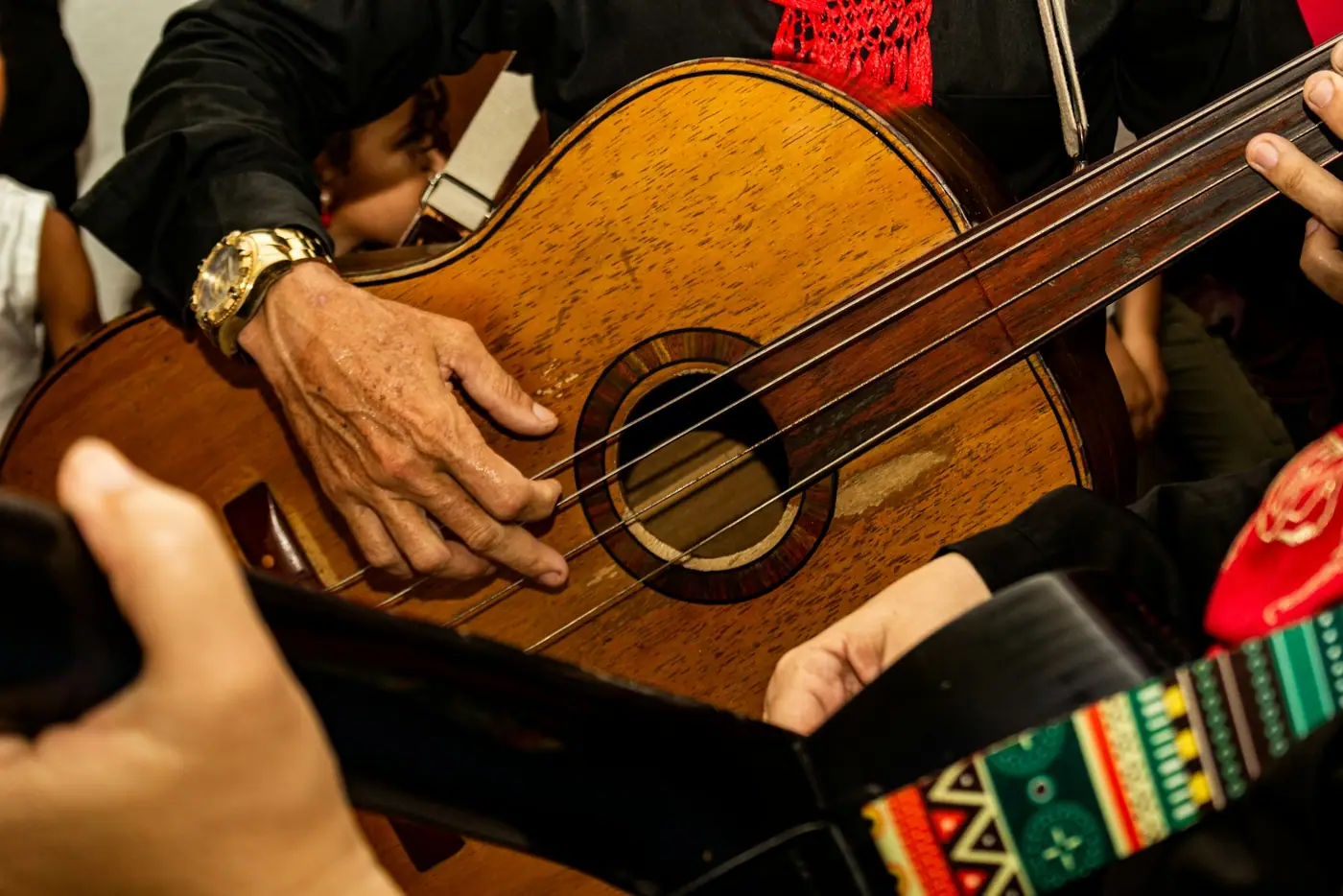 A group of people gathered around a man playing a guitar.