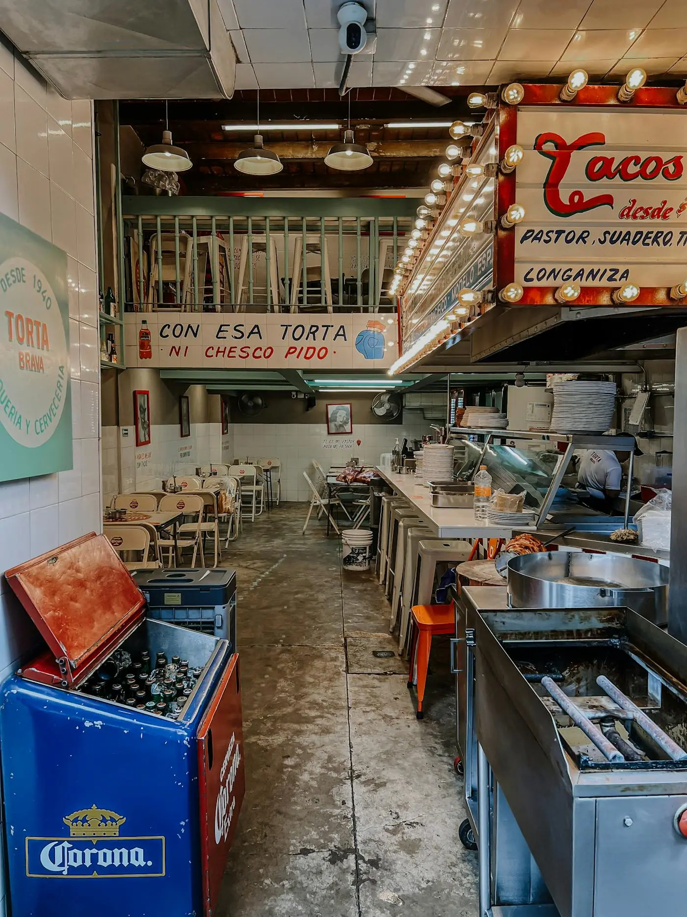 A colorful taquería counter in Mexico with people and bright signs.