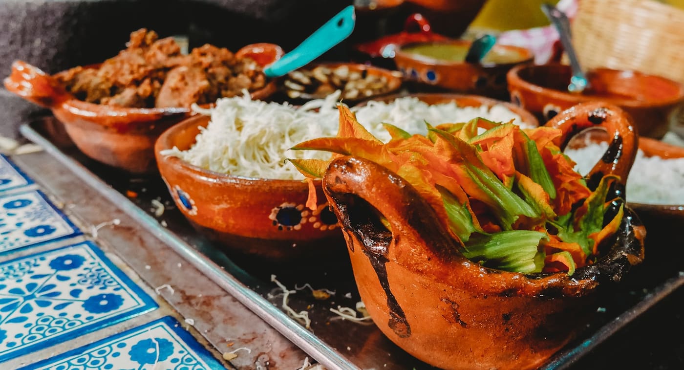 Several small Mexican dishes served in clay bowls on a talavera-tiled table.