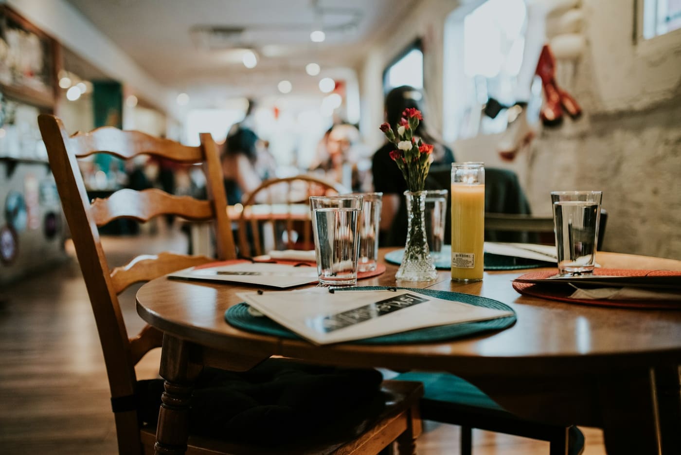 A plain restaurant table set with water glasses and simple place settings.