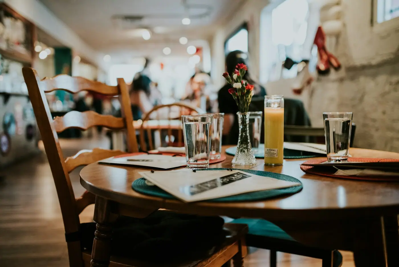 A plain restaurant table set with water glasses and simple place settings.
