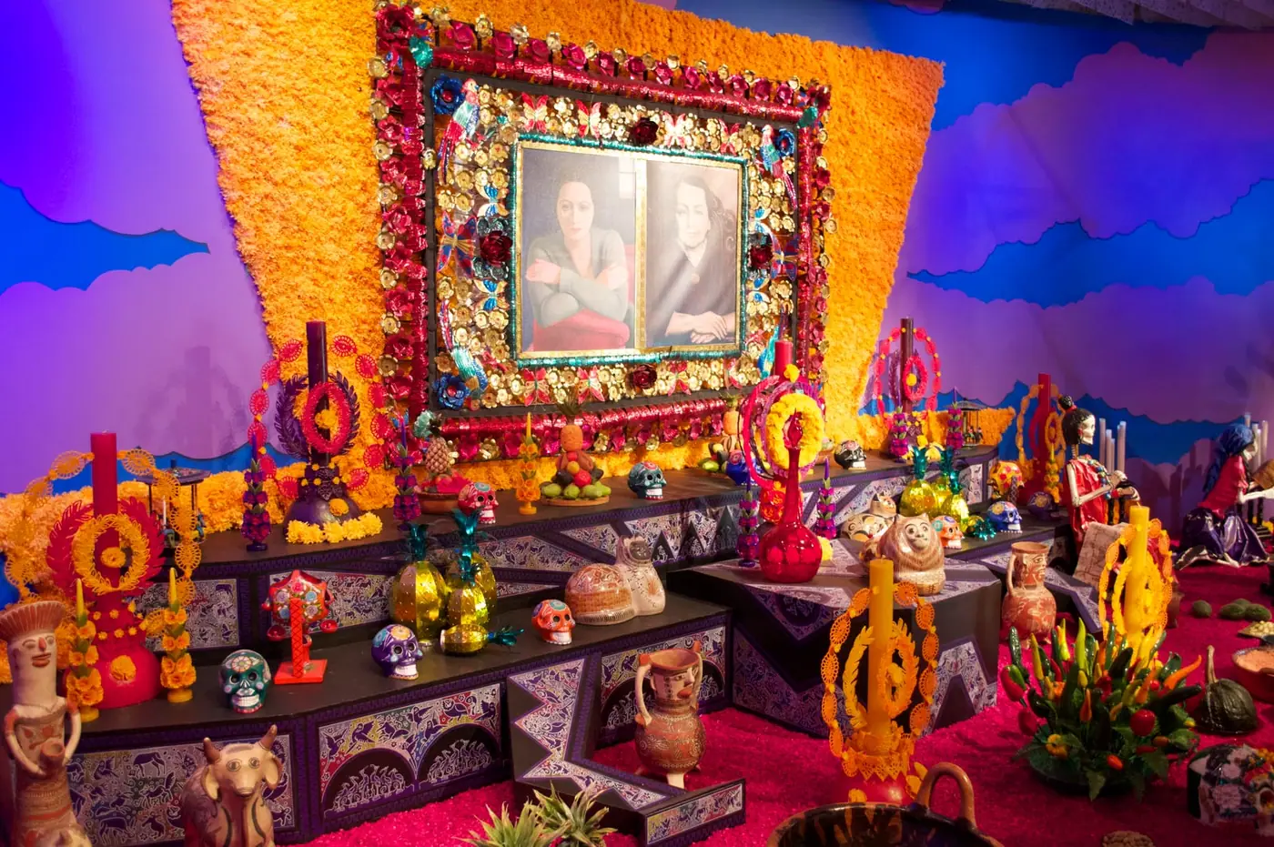 A home Day of the Dead altar with framed photographs, sugar skulls and marigolds