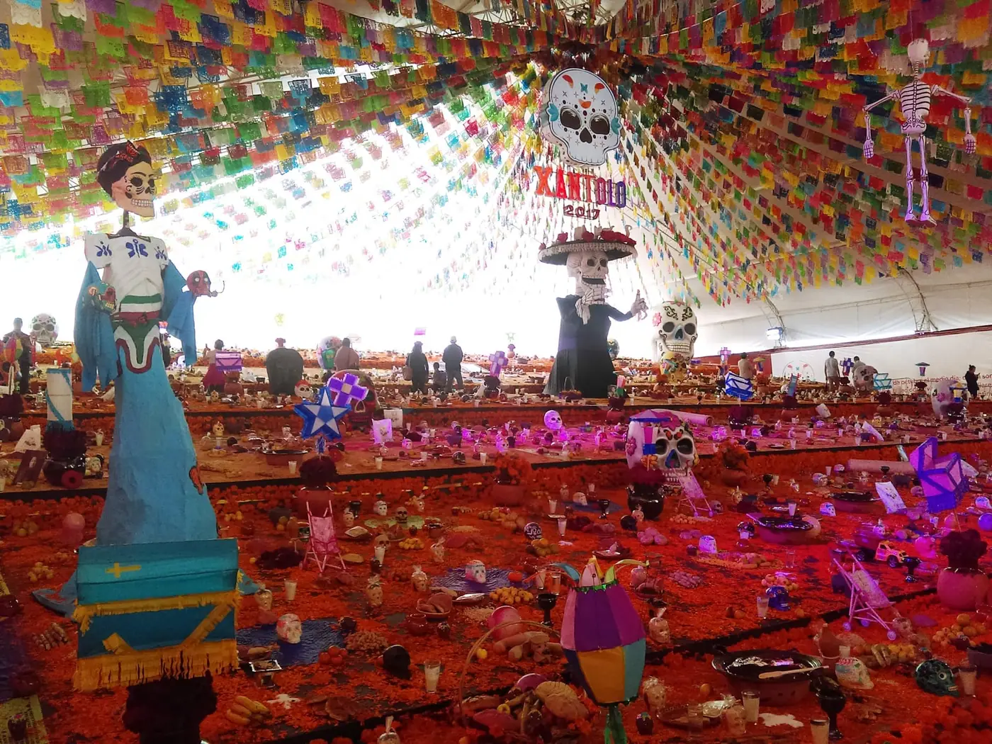 A large multi-level public ofrenda in a plaza, covered in candles and marigolds