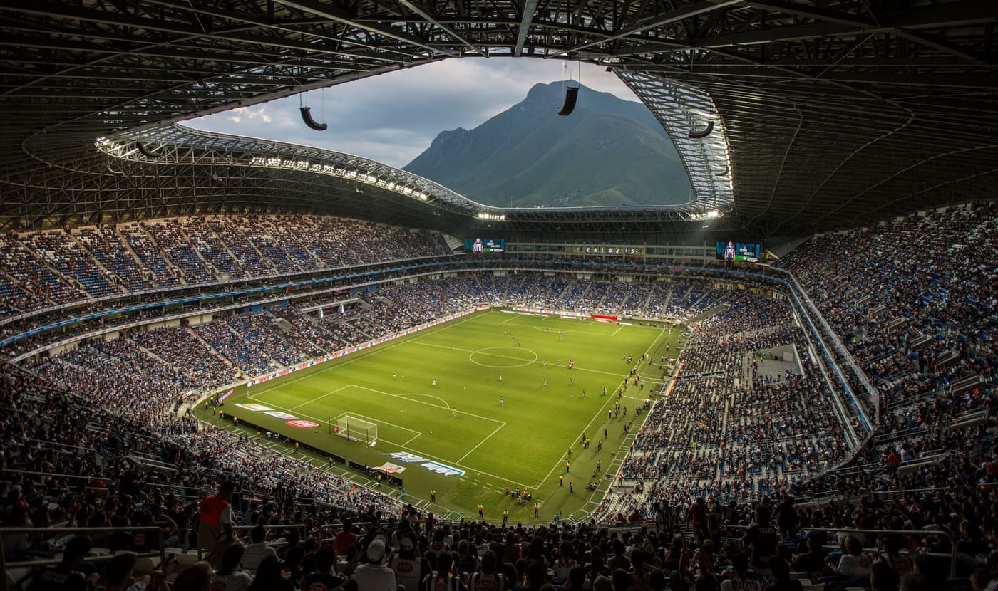 A full Estadio BBVA seen from the upper stands, with the Cerro de la Silla framed in the opening behind the pitch