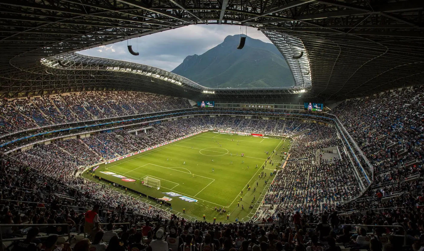 A full Estadio BBVA seen from the upper stands, with the Cerro de la Silla framed in the opening behind the pitch