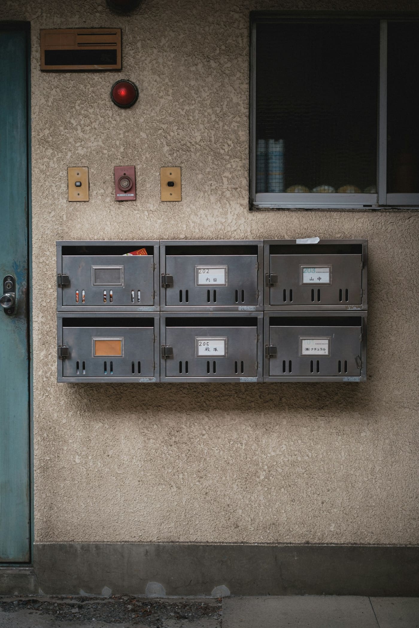 A bank of metal utility meter boxes mounted on a concrete building wall.