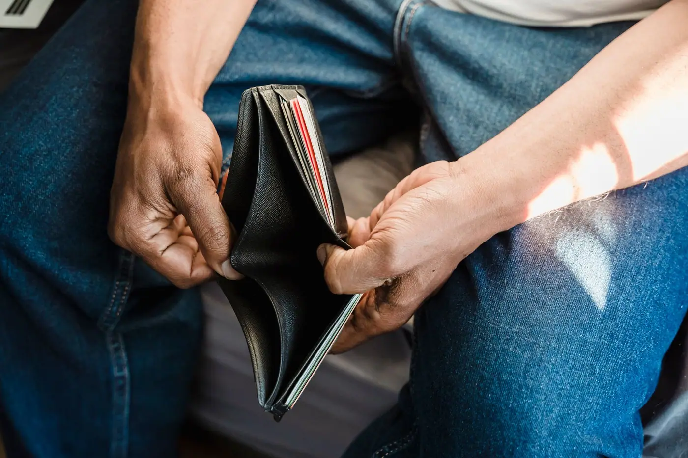 A pair of hands holding an open wallet with nothing in the note compartment
