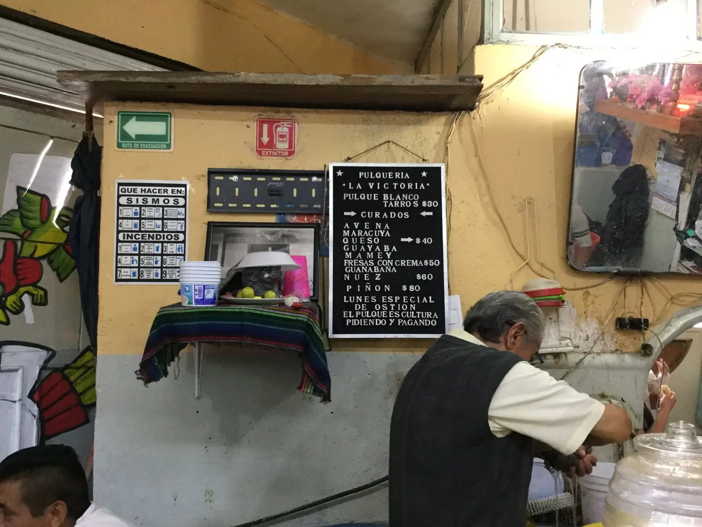 The interior of a Mexico City pulqueria with a hand-written price board