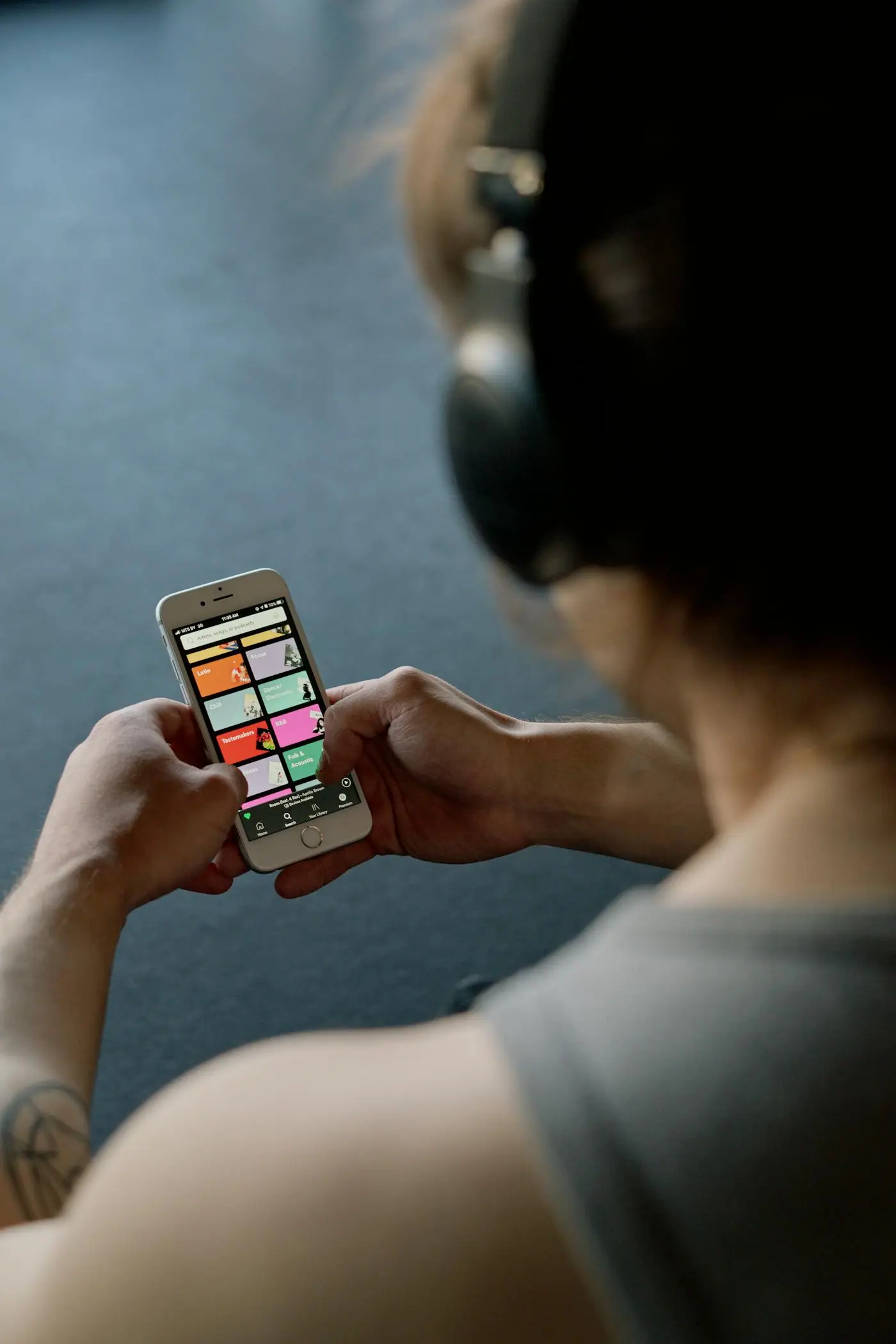 A person listening through headphones while holding a smartphone.