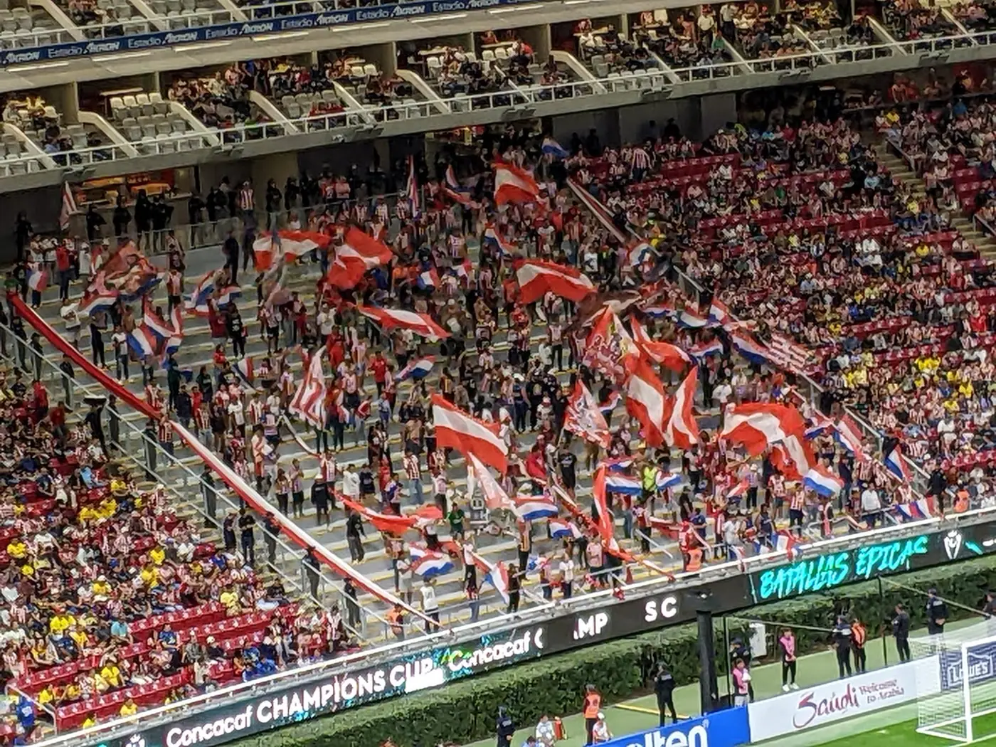 Supporters waving red and white flags in the stands at a Chivas match