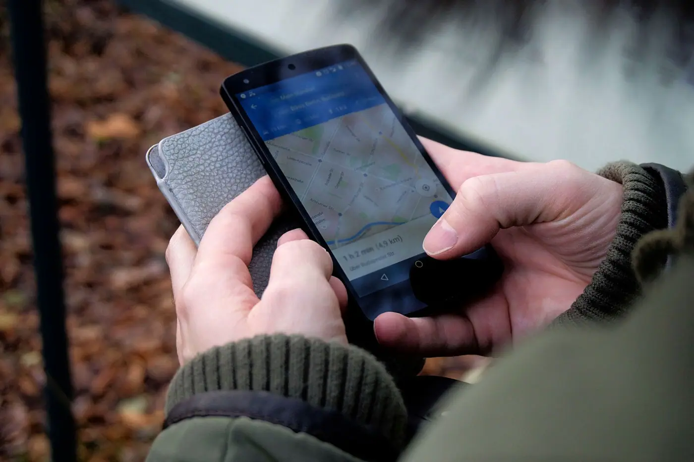 Two hands holding a phone showing a map app with a route on the screen