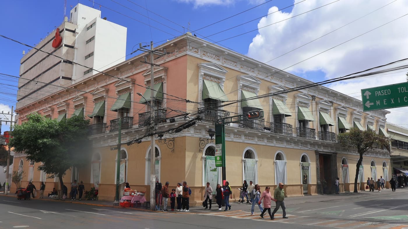 A historic colonnaded stone building on a street corner in Mexico.