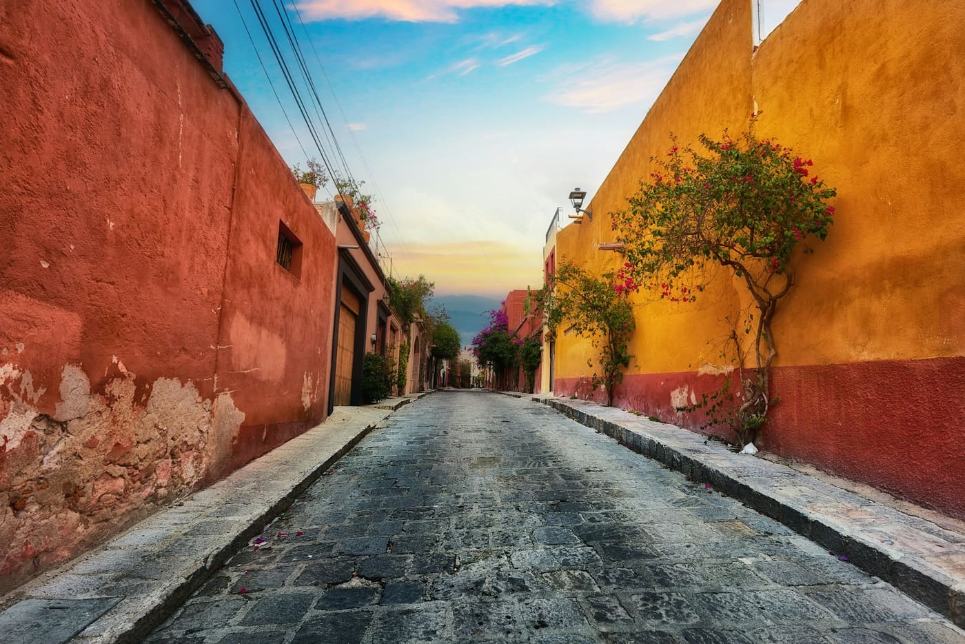 A narrow cobbled street running between red and yellow painted walls in Mexico.