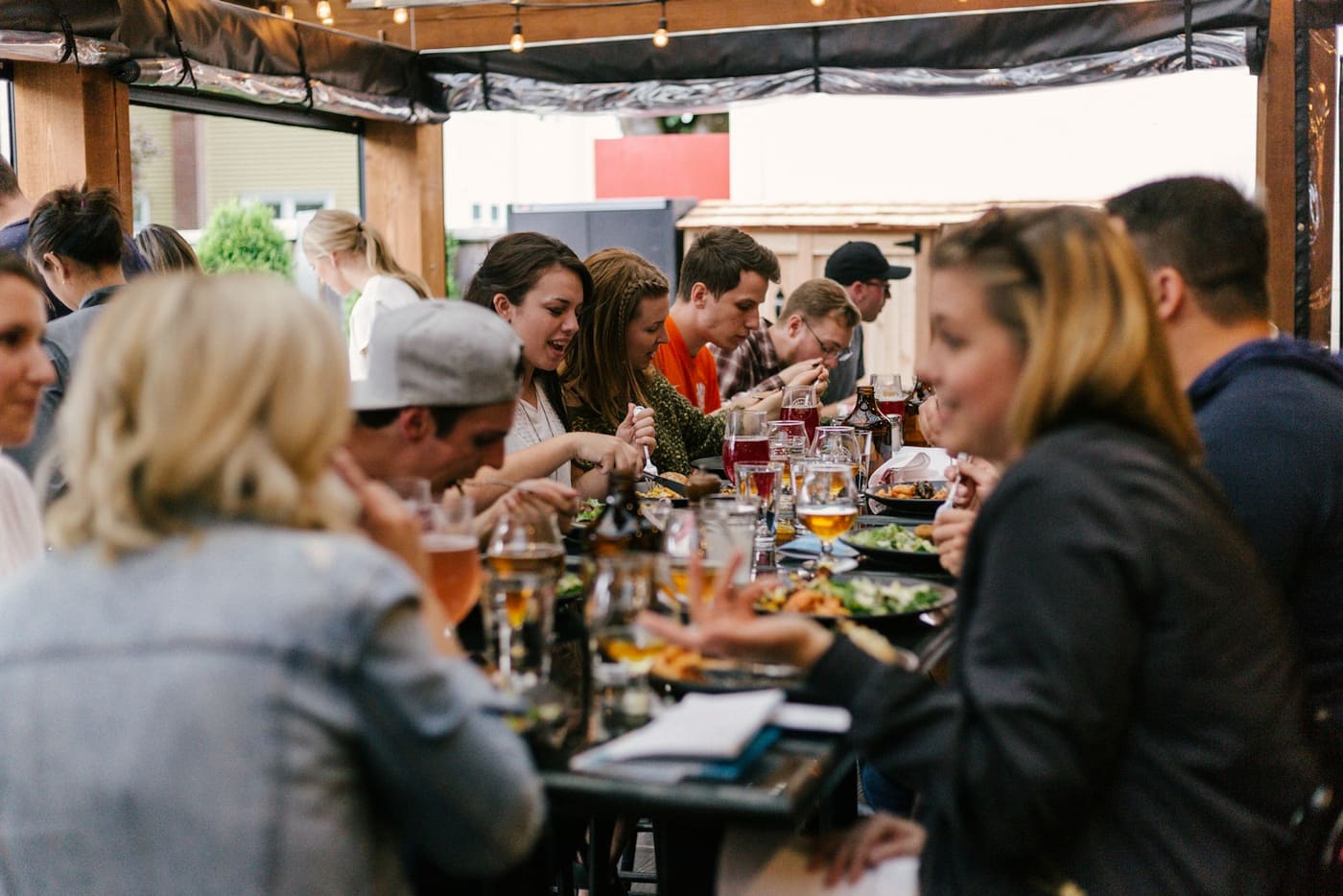 A long communal table crowded with people eating and drinking together.