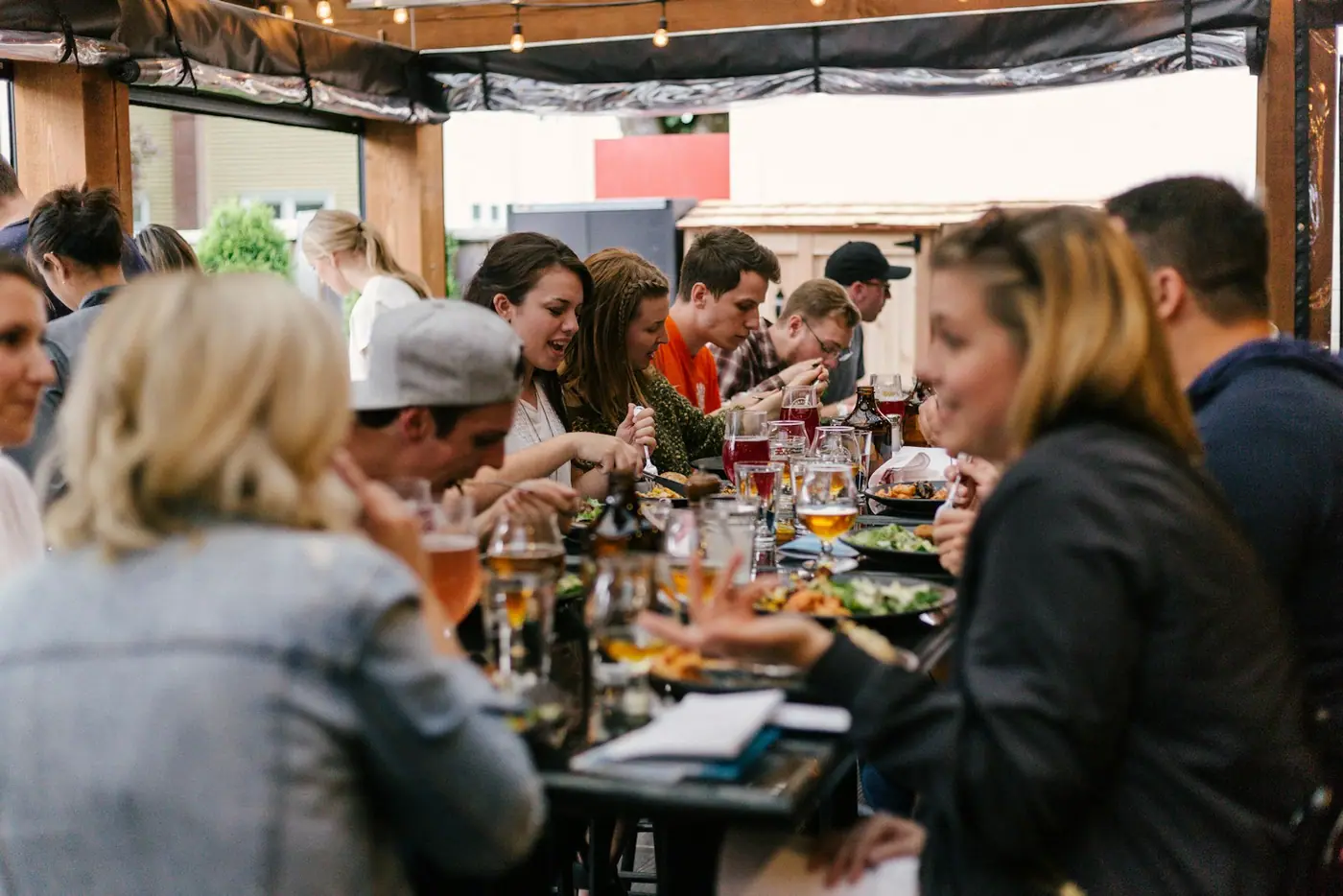 A long communal table crowded with people eating and drinking together.