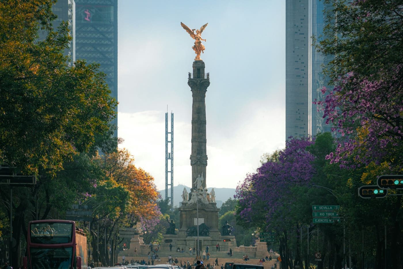 A wide Mexico City avenue with the Ángel de la Independencia monument in the distance.