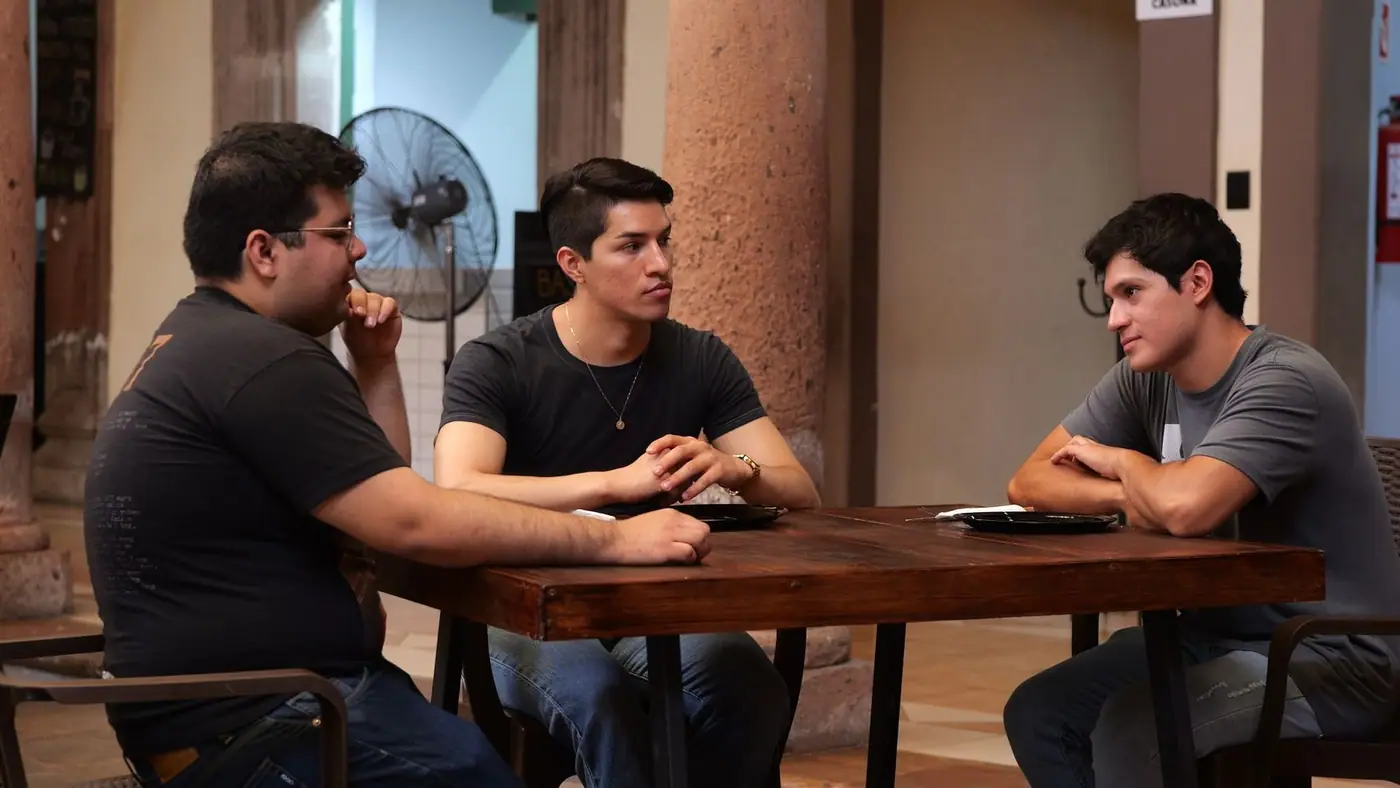 Three men talking around a table in a restaurant in Guanajuato.