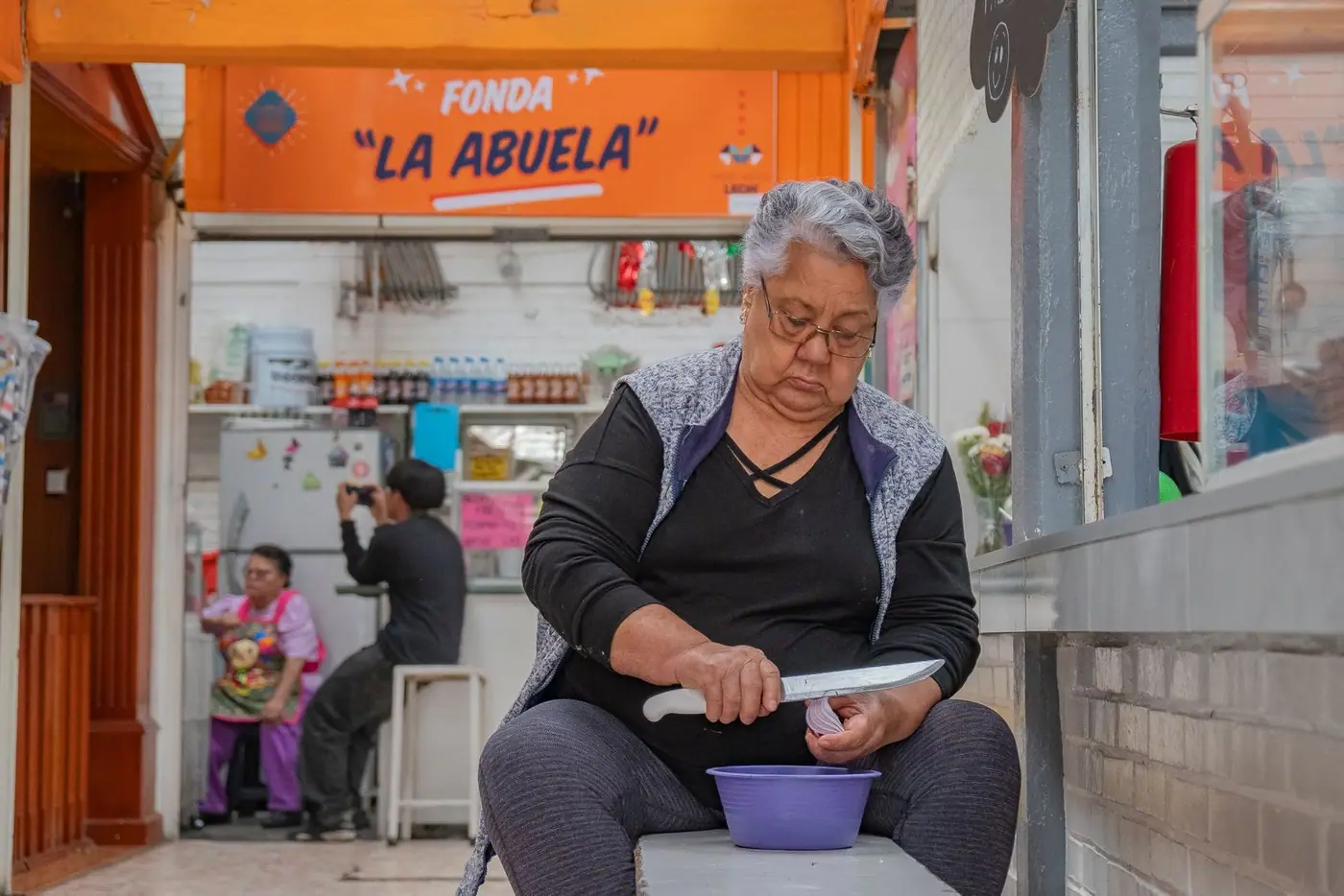 A woman preparing food at a market fonda in Guanajuato under a sign reading Fonda La Abuela.