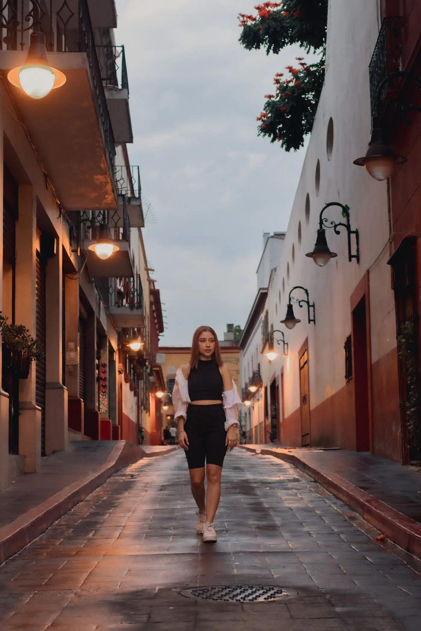 A woman walking along a historic street in Mexico City at dusk.