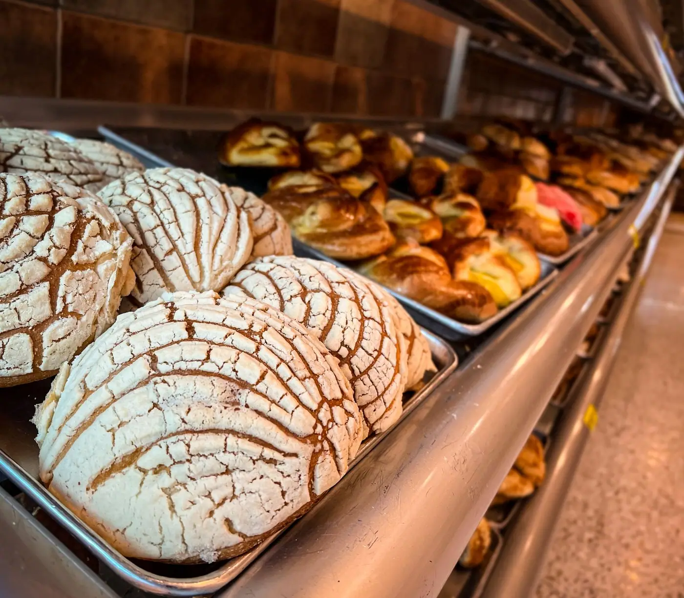 Trays of conchas and other sweet breads on shelves in a Mexico City bakery.
