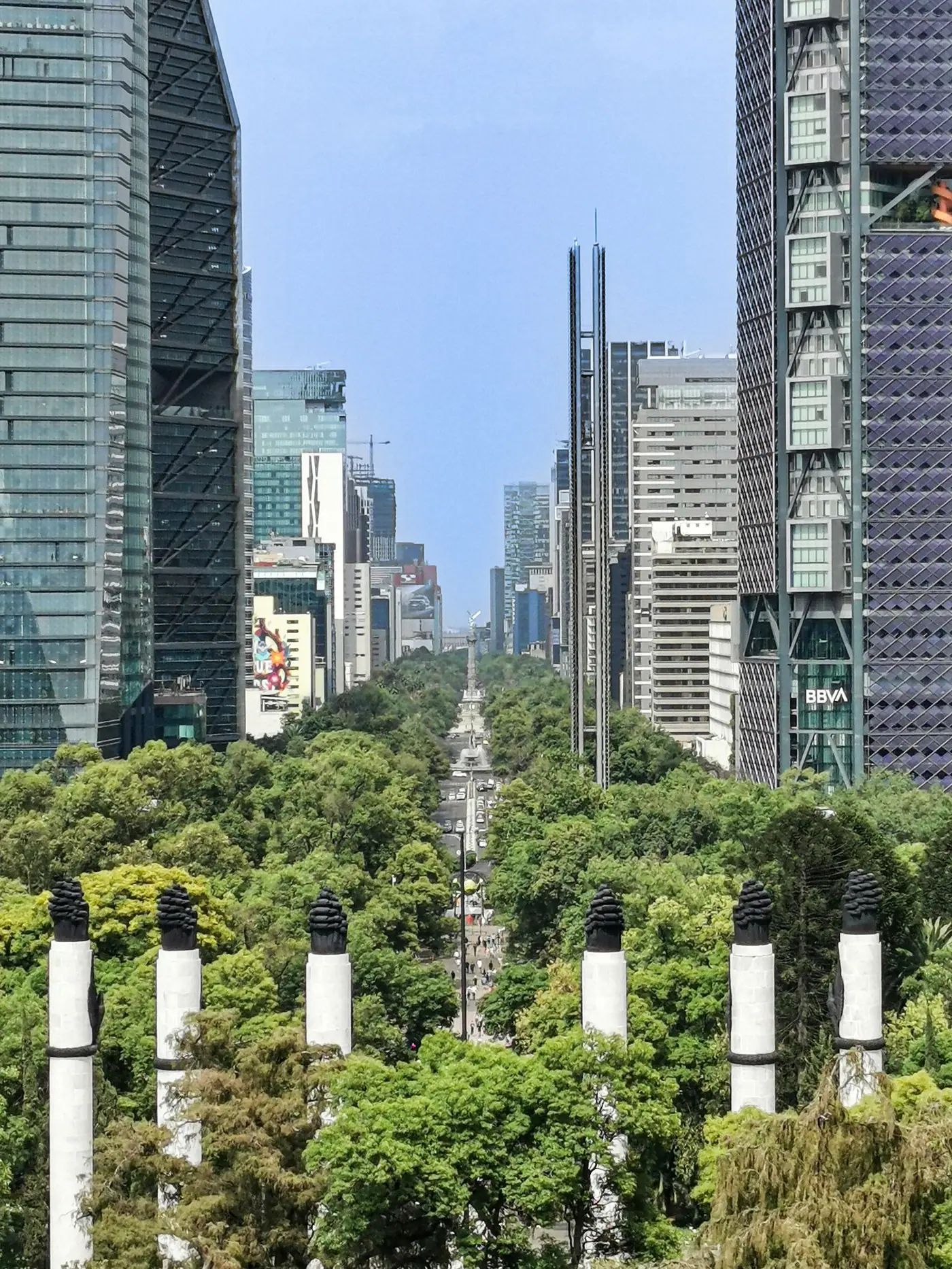 A wide view along Paseo de la Reforma in Mexico City with skyscrapers and trees.